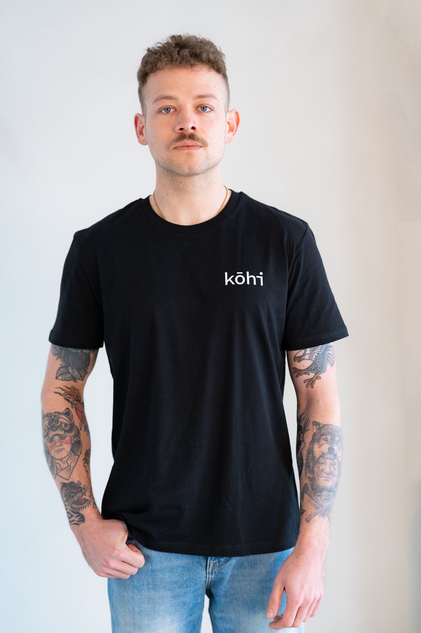 Männliches Model trägt schwarzes Tshirt mit kohi-Logo auf der Brust.