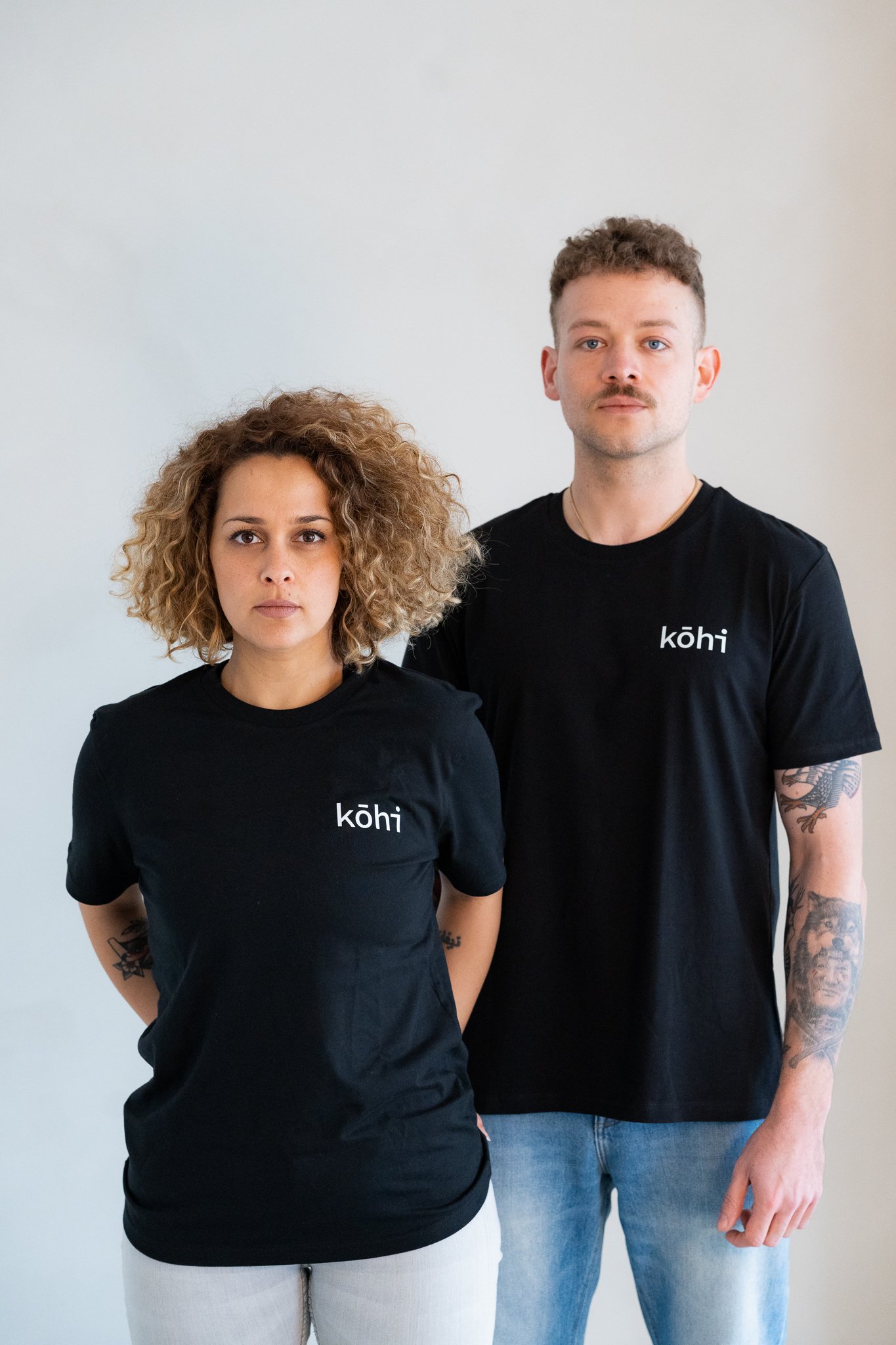 Paar trägt schwarzes Tshirt mit kohi-Logo auf der Brust.