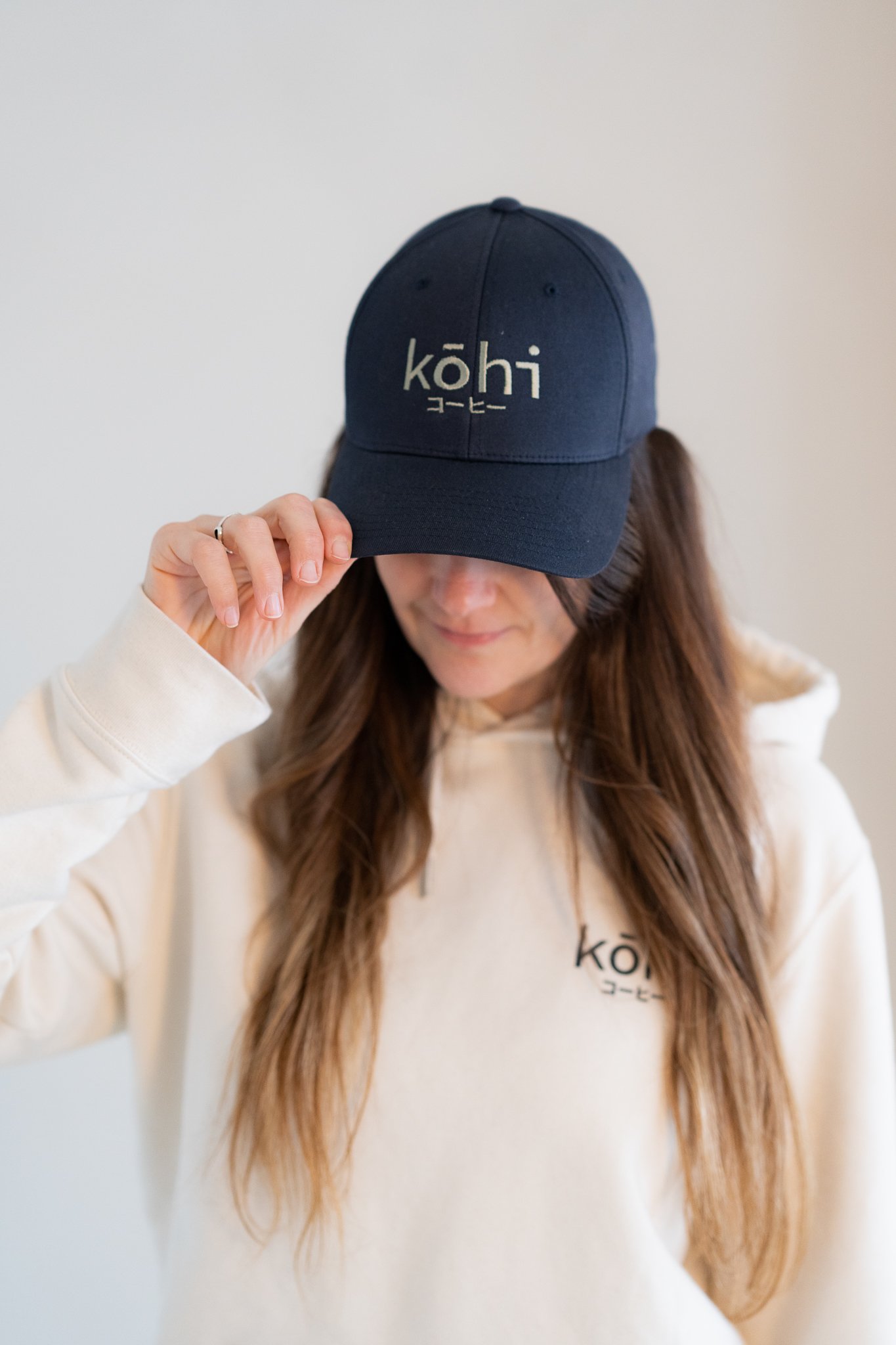 Model trägt navy-farbene Cap mit salbeifarbenen kohi Schriftzug