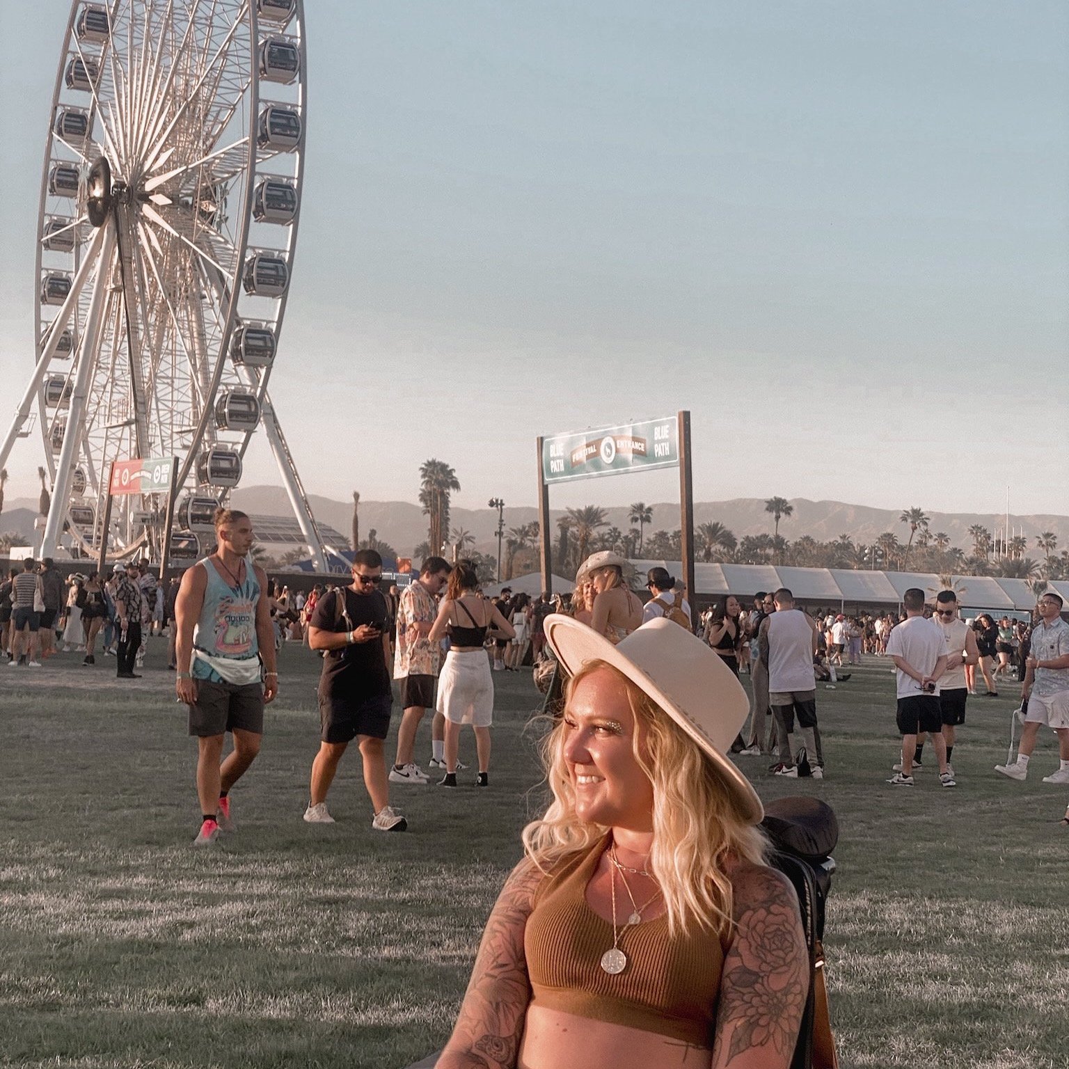 Shailynn looks over her right shoulder with a broad hat on and Coachella Ferris wheel in the background