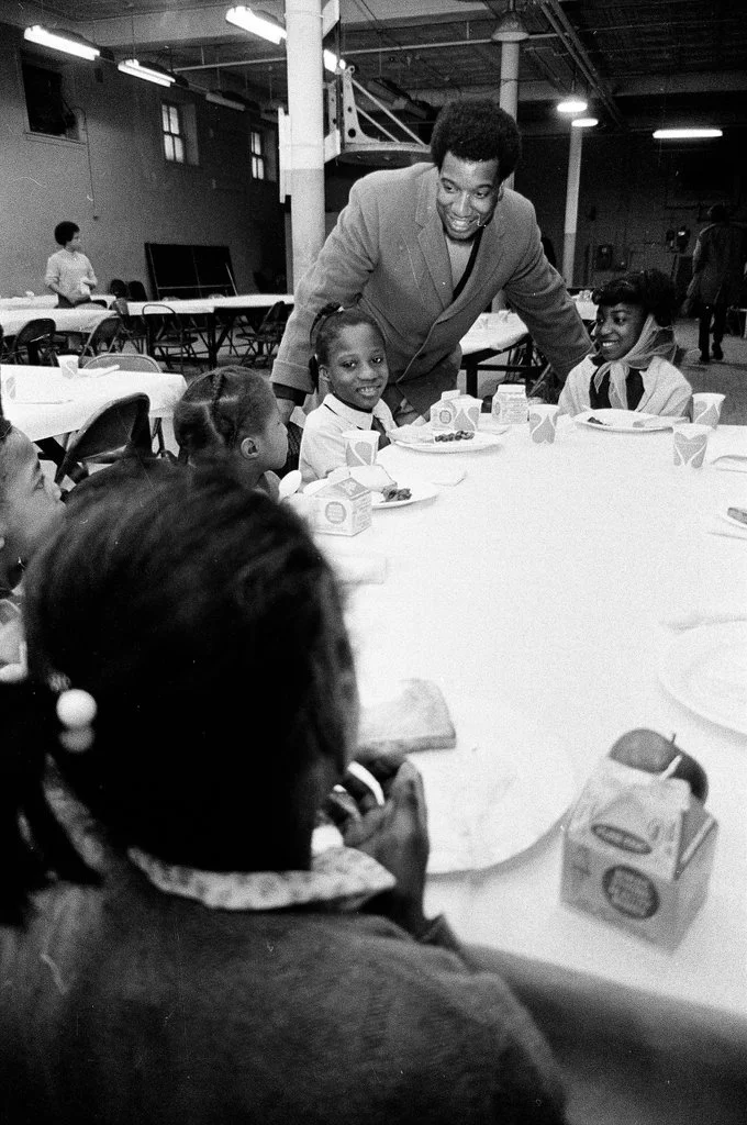 On April 1, 1969, Fred Hampton talks with children on the first day of the Illinois Chapter's Free Breakfast for Children Program at the Better Boys Foundation, the program's first location. The Illinois Chapter served 83 children on the first day an