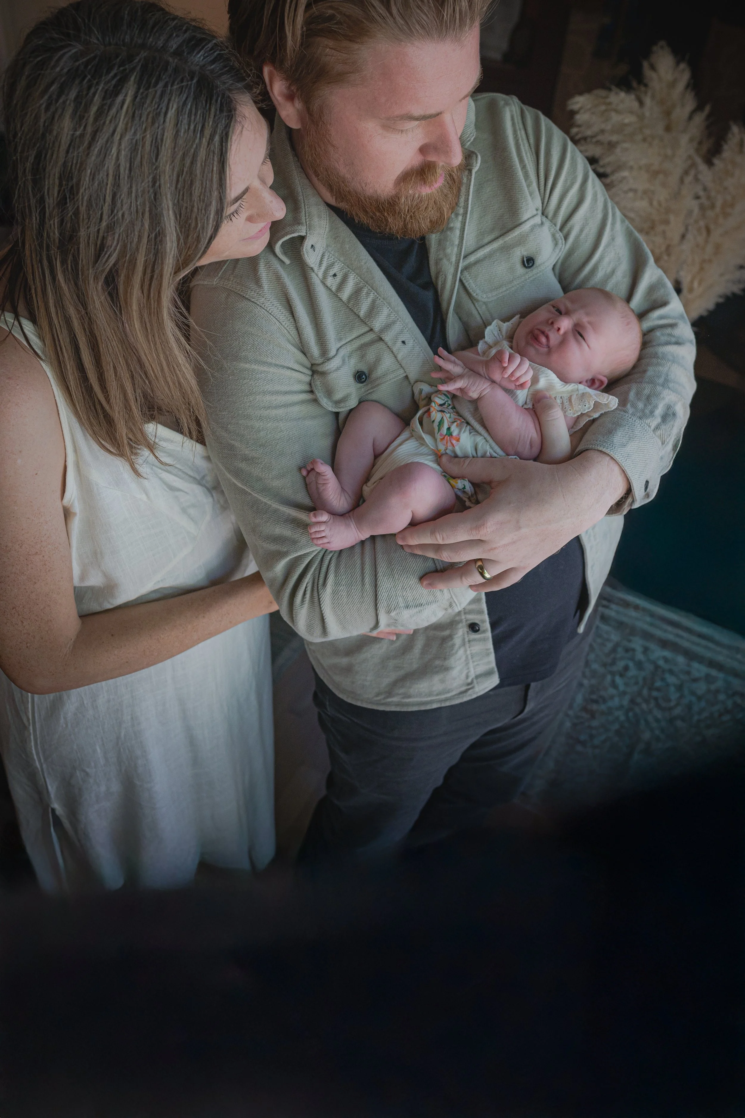 A couple holding a crying baby in their arms.
