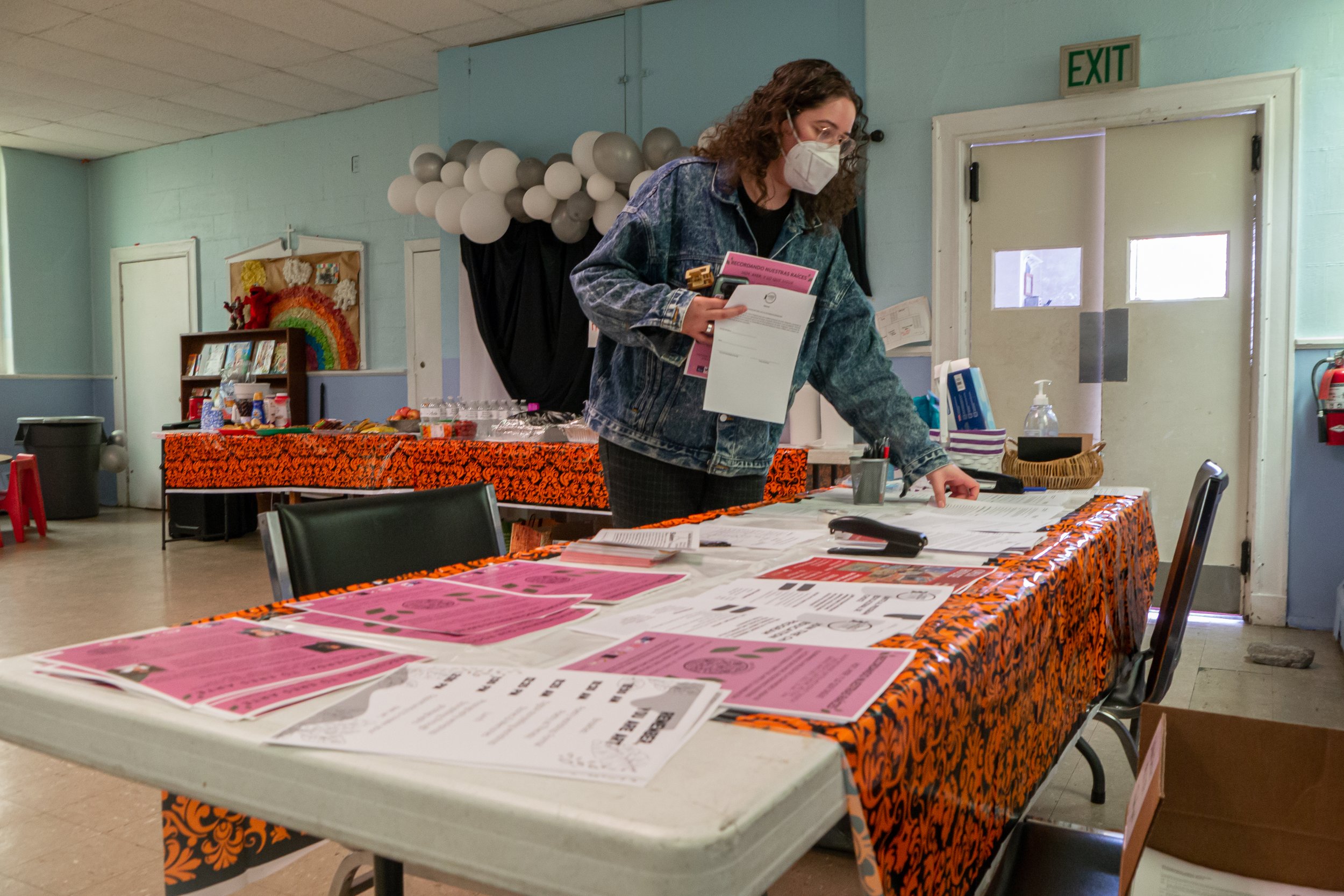 Julissa Gomez Ruvalcaba, the organizer for the event, placing information sheets and flyers for the upcoming event Raices y Recuerdos