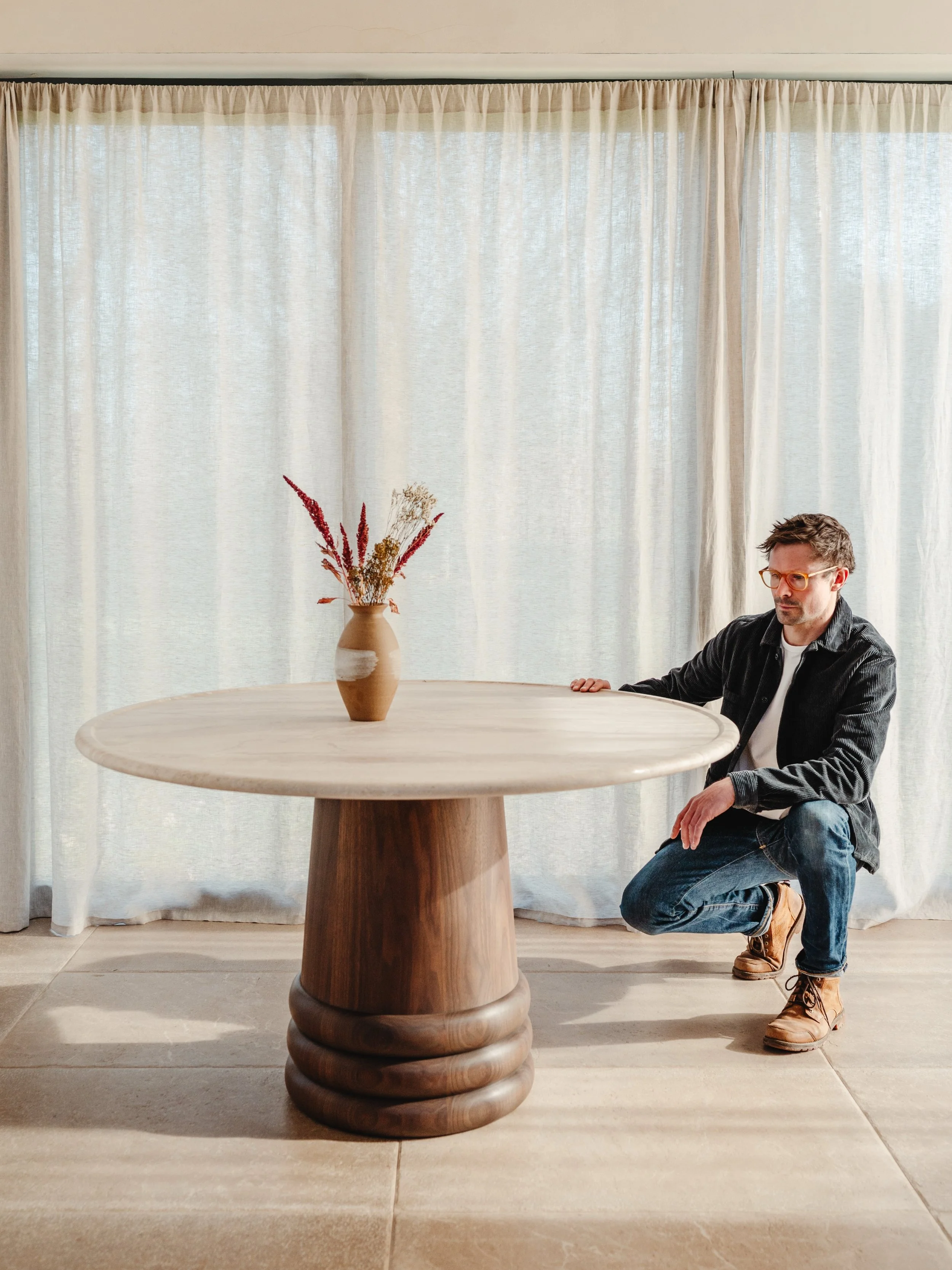 The Fraser dining table &mdash; where refined craftsmanship meets the natural beauty of stone and timber. Featuring Breccia Sarda marble from Sardinia, Italy, its warm cream and brown hues pair effortlessly with the solid hand-turned coopered walnut 