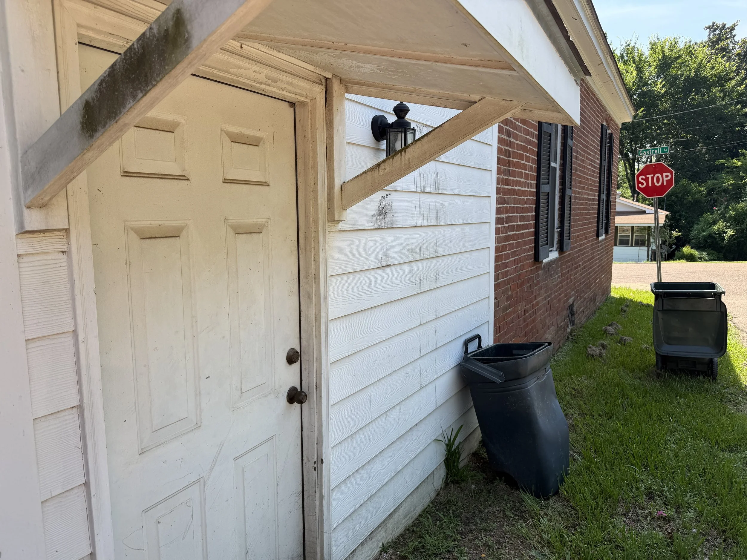 Front garage area with white garage door, brick wall, and exterior surfaces before cleaning.