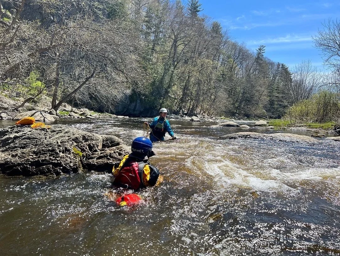 Two people practice whitewater rescues on a river.