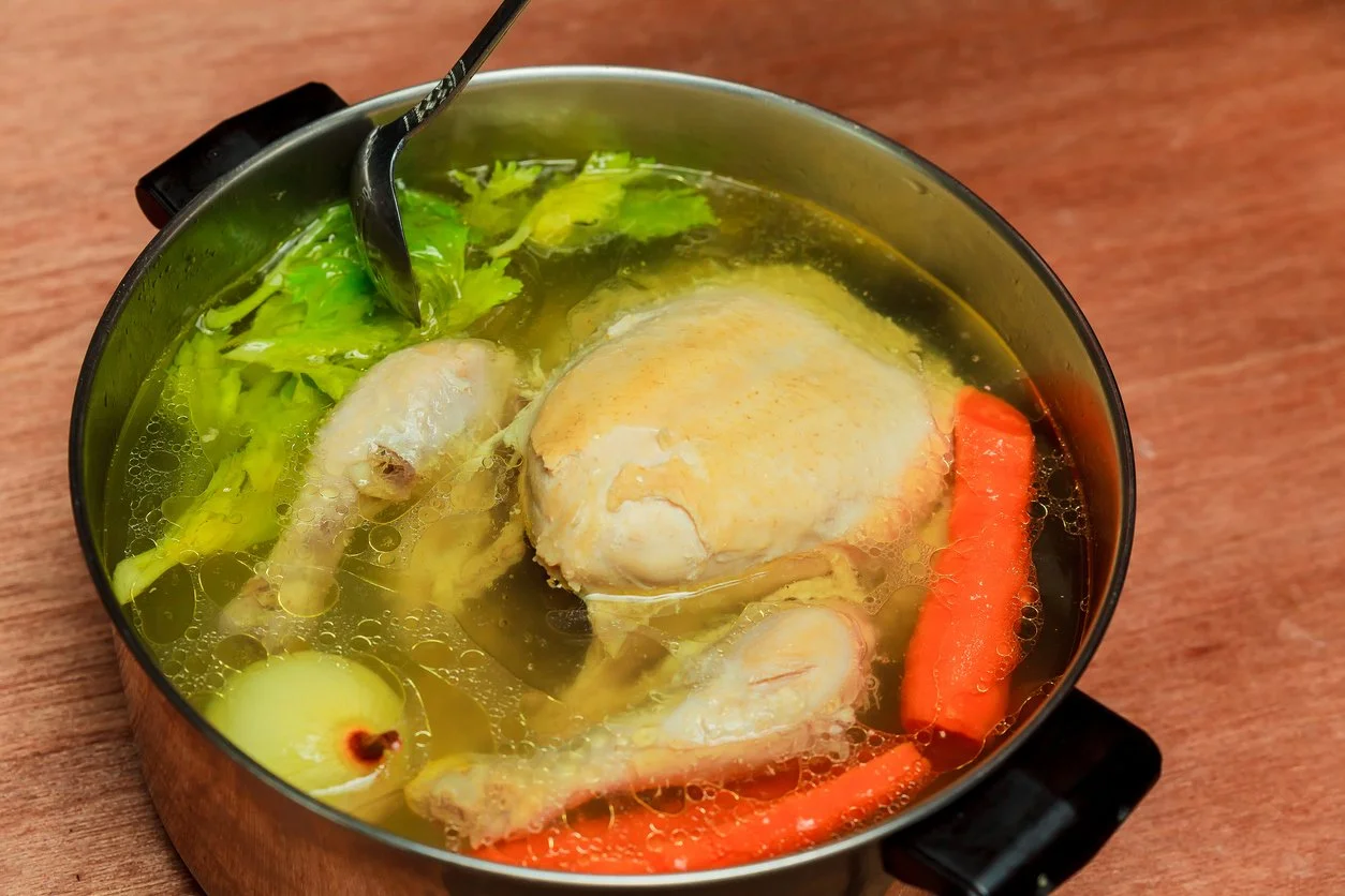 chicken in a pot of water with soup vegetables
