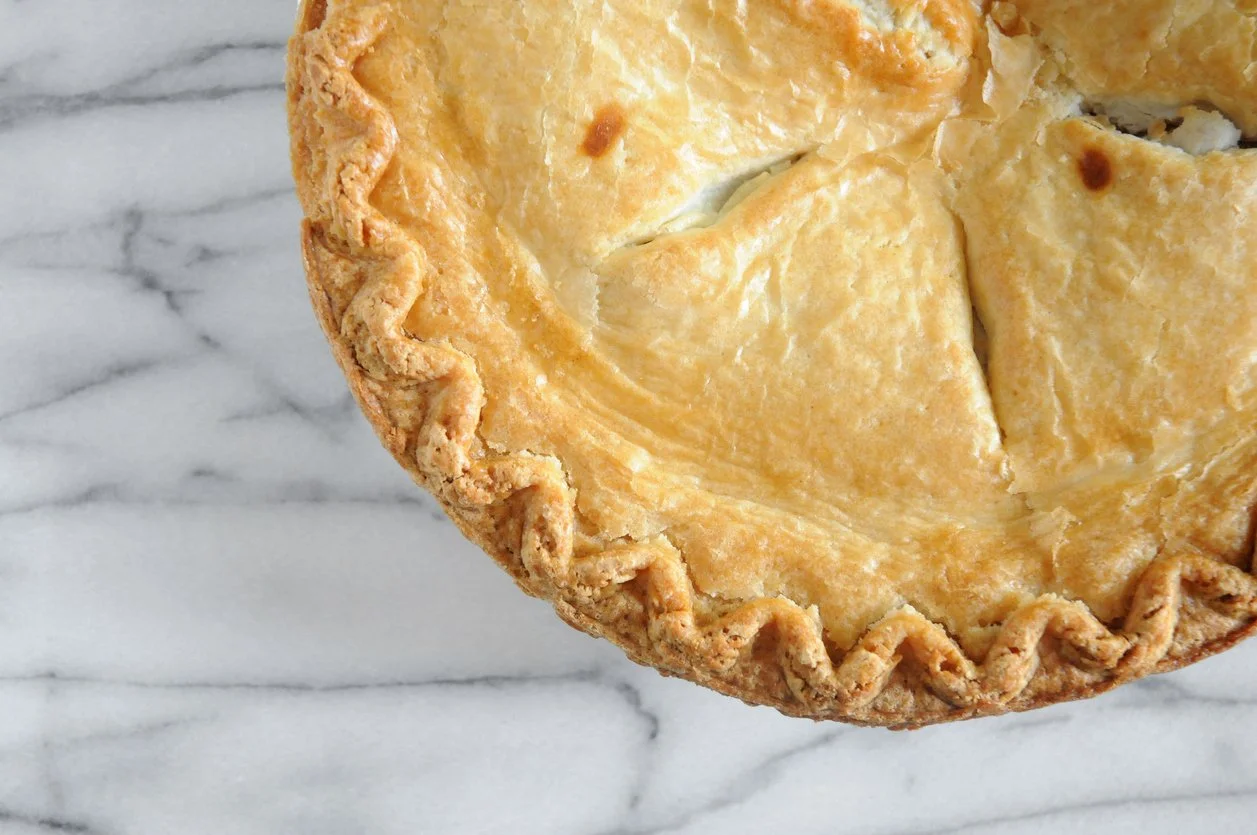 a baked pie with a crisp golden crust on a marble counter