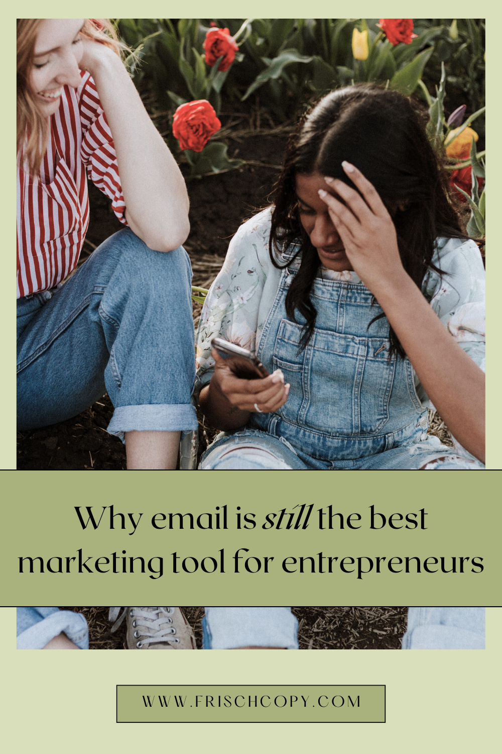 Two women are sitting together outside. One woman is holding a phone, and they're both smiling while looking at the screen