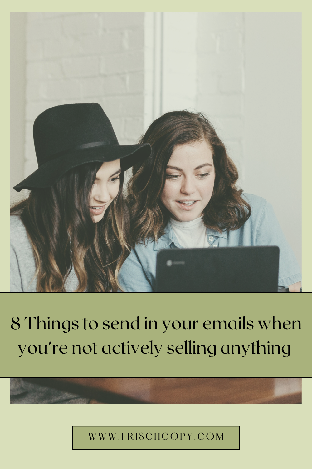 Two women sitting together, seeming happy, looking toward a laptop screen that we cannot see
