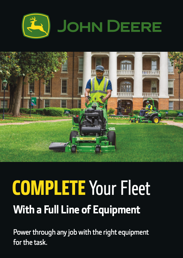 An operator mowing grass on a university campus using a John Deere QuikTrak™ stand-on mower.
