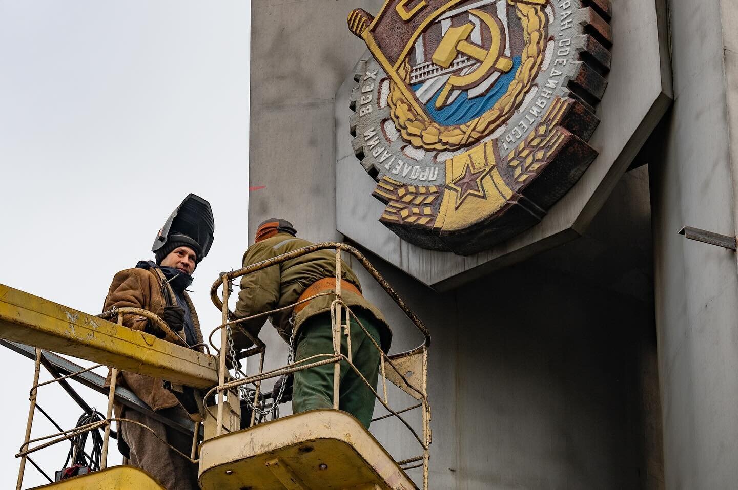 Construction workers prepare to cover Soviet-era symbolism at the New Kramatorsk Machinebuilding Factory (NKMZ) in Kramatorsk, Donetsk Oblast, eastern Ukraine. Each symbol on this obelisk represents a Soviet state decoration awarded to the factory fo