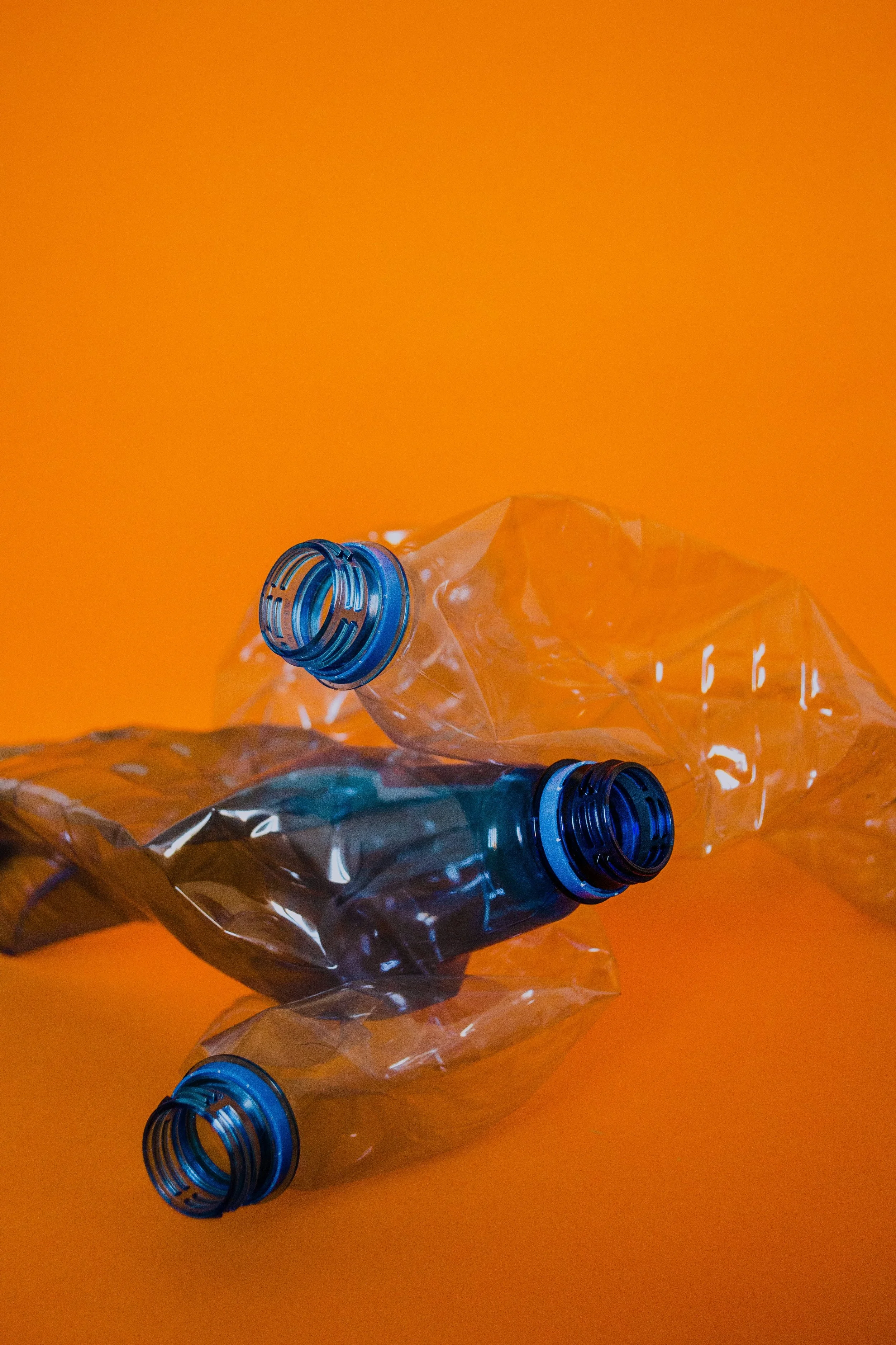 Scrunched up plastic bottles on an orange background