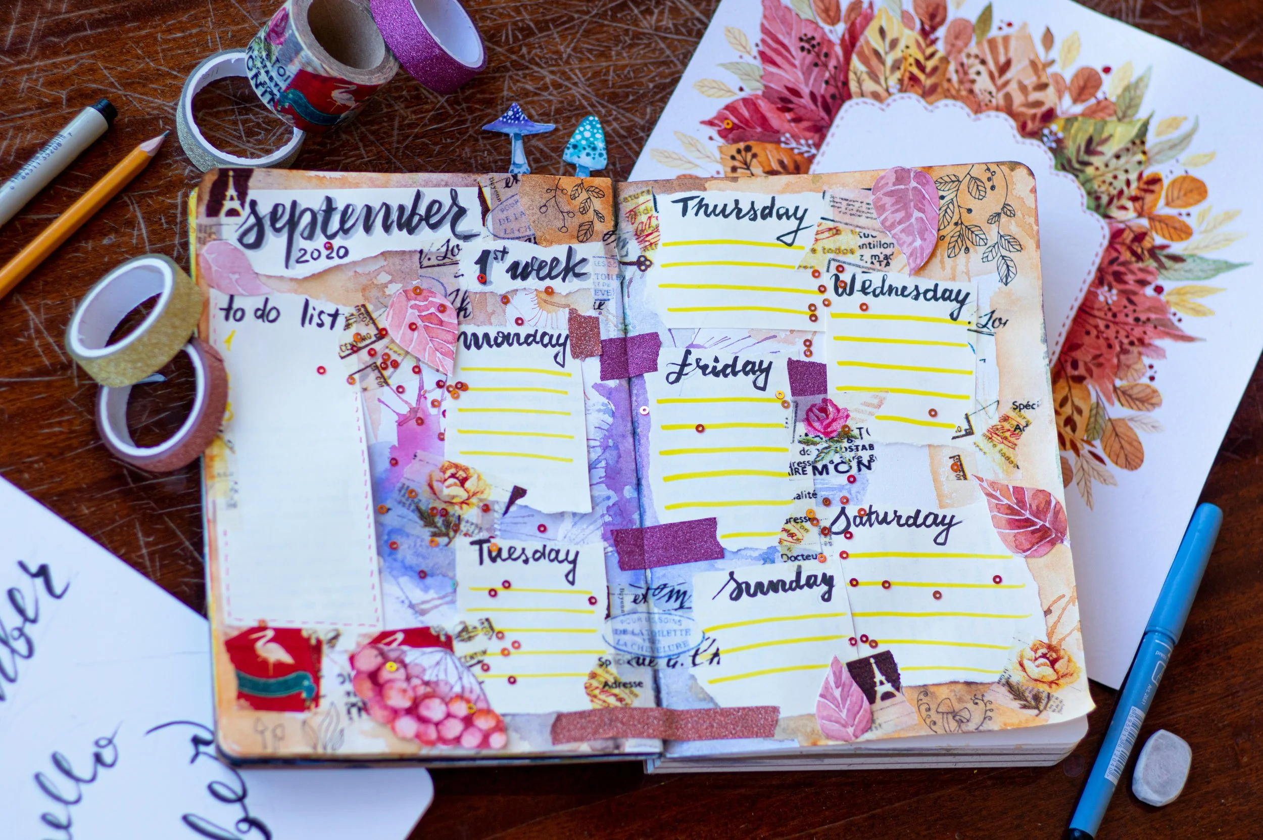 An open scrapbook on a table with pens and washi tape