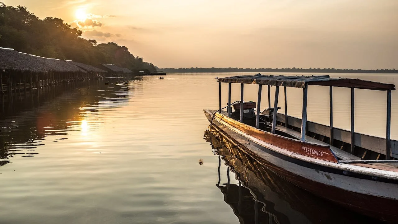 Bateau traditionnel sur les eaux paisibles du Cambodge au coucher du soleil