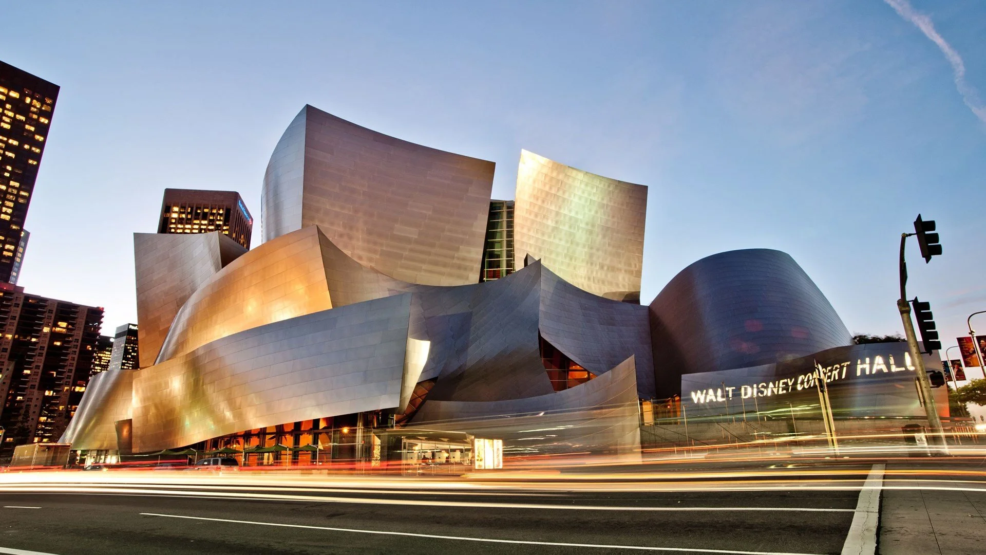 Twilight view of illuminated Frank Gehry designed Los Angeles Music Center with car lights streaking in the foreground