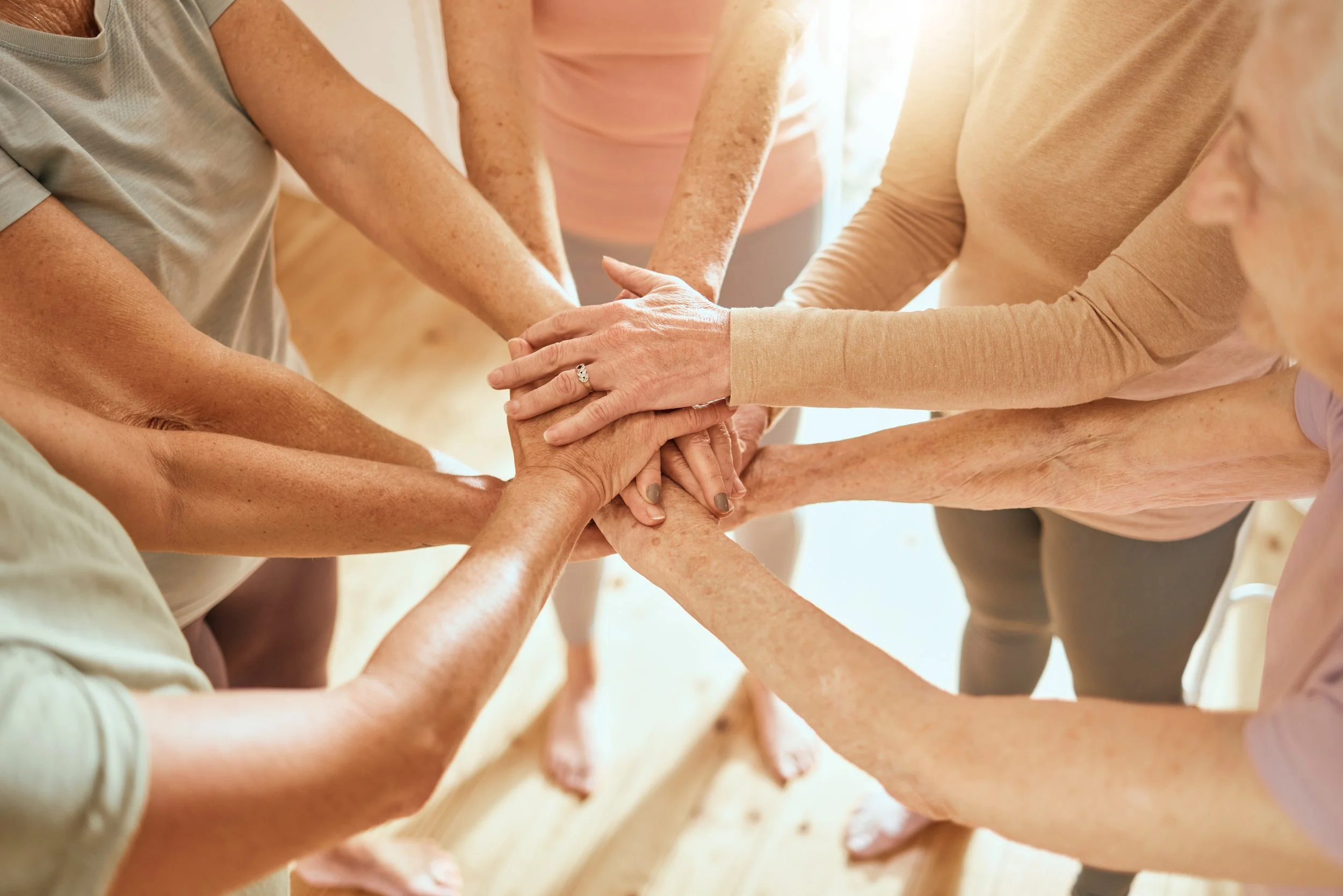 Persone anziane che si tengono le mani in cerchio, simbolo di unità e solidarietà.
