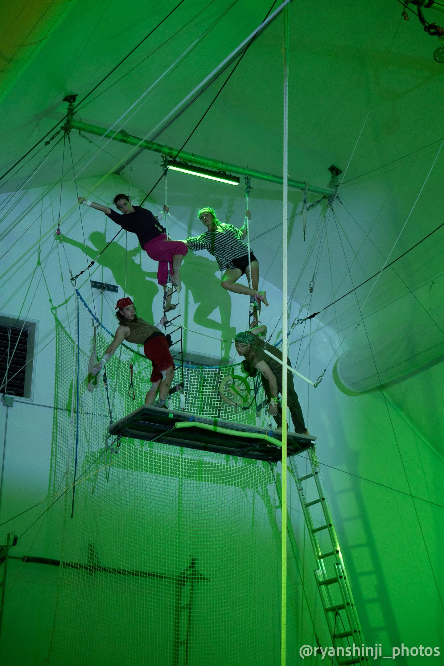 Pirate costumed acrobats pose on a flying trapeze platform