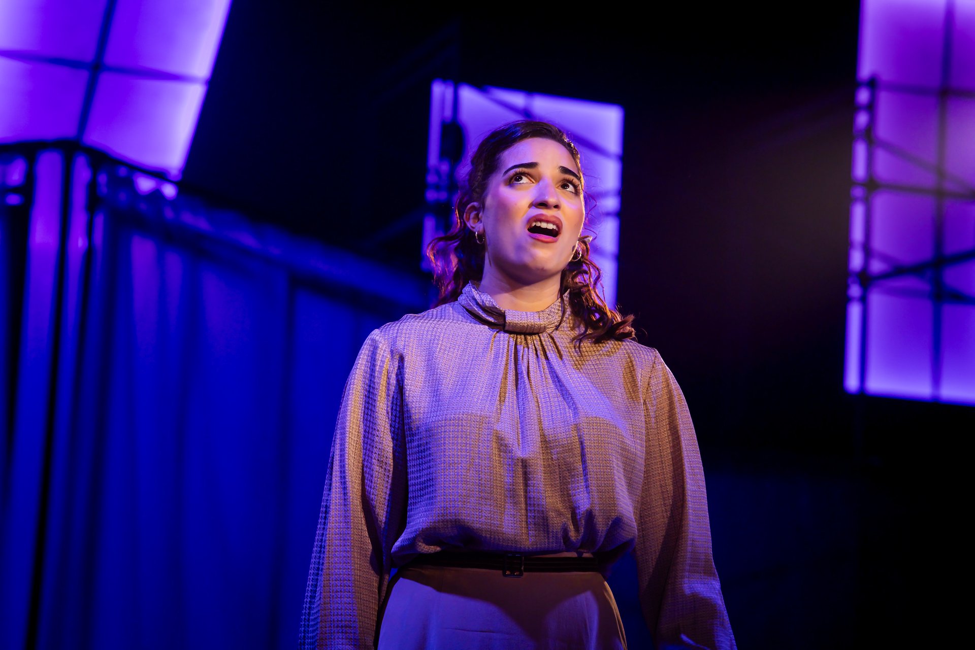 Performer singing a solo under purple stage lights in American Psycho at Shenandoah Conservatory