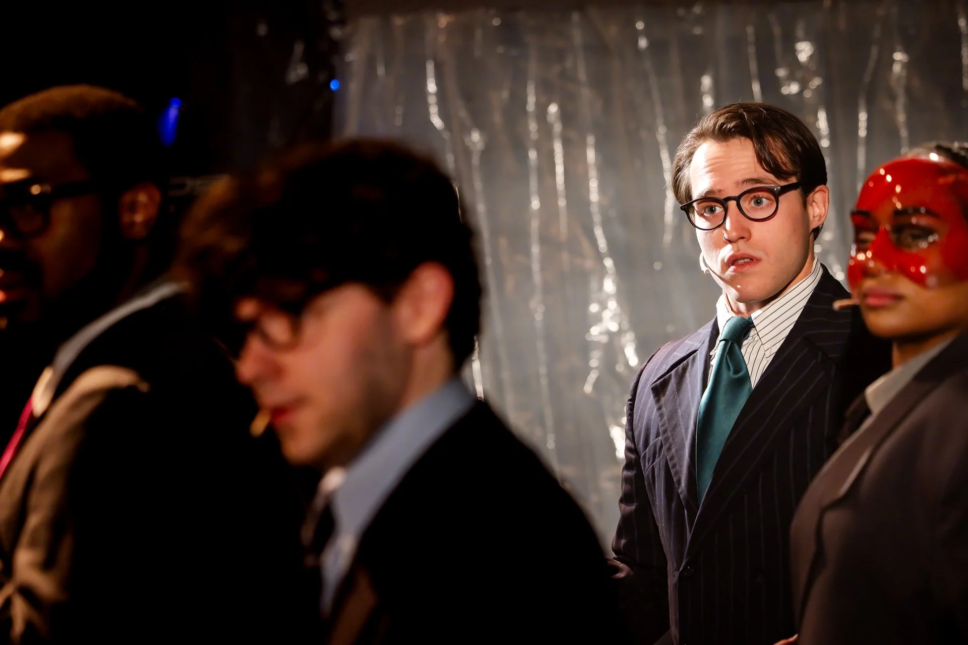 Wall Street characters in suits and glasses, one in a red mask, in American Psycho at Shenandoah Conservatory