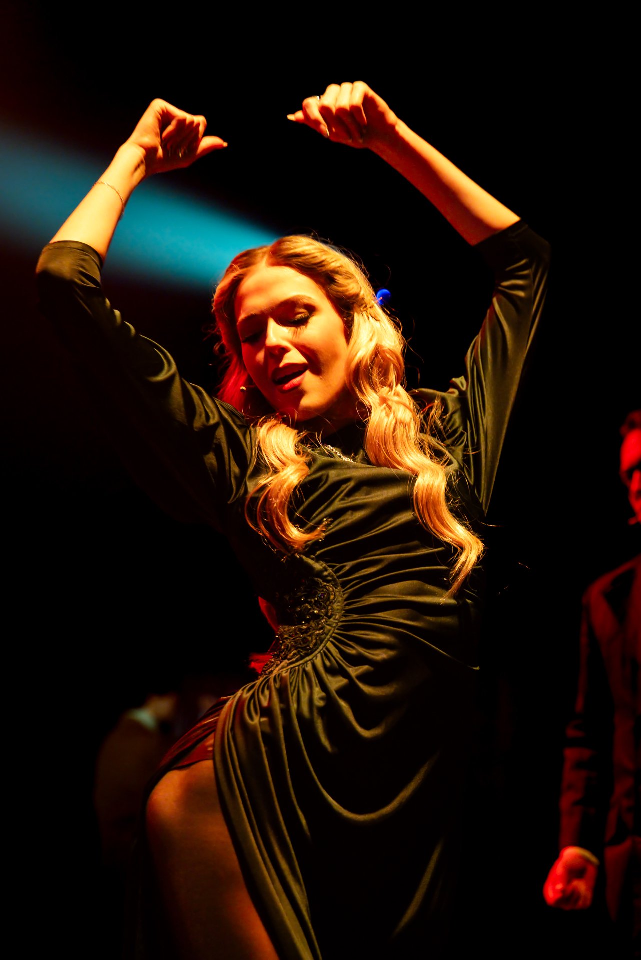 Performer in a green dress dancing under a spotlight in American Psycho at Shenandoah Conservatory