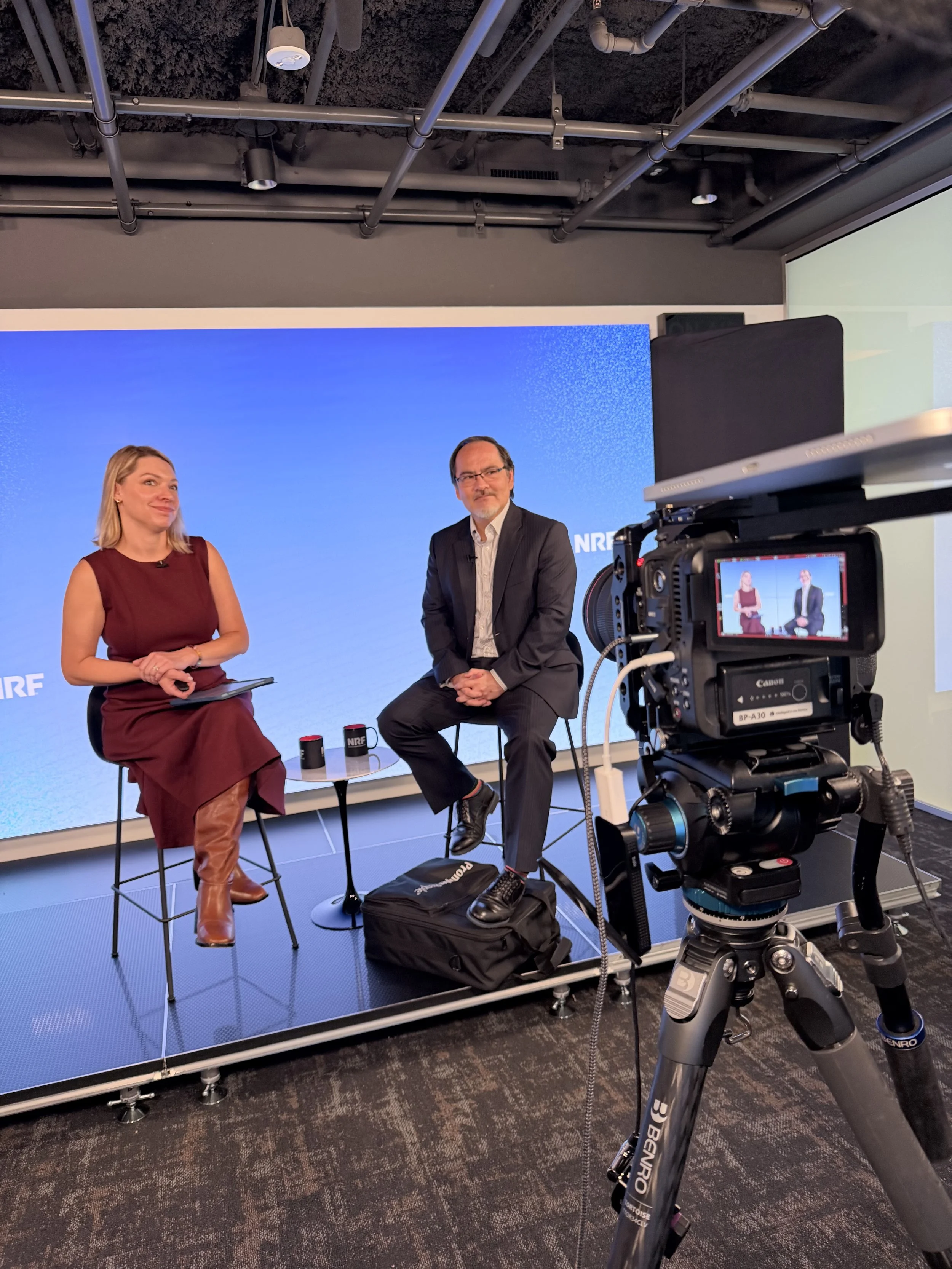 Two presenters seated on stools for a studio conversation, filmed on a Canon cinema camera in Washington, DC, by C King Media