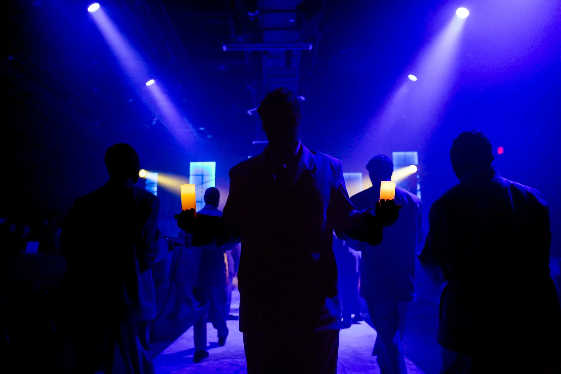 Silhouetted cast under blue nightclub beams and haze in American Psycho at Glaize Studio Theatre