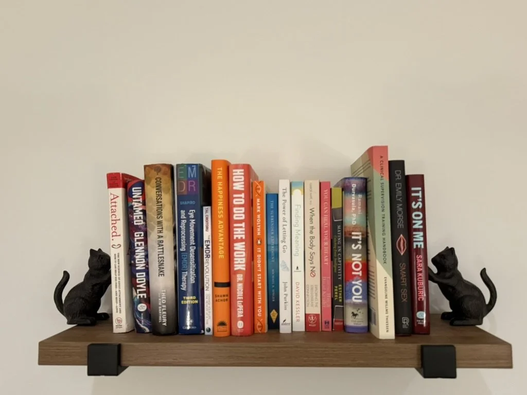 Books on trauma, attachment, EMDR, and mental health displayed on a shelf at Lokahi Wellness Collective.