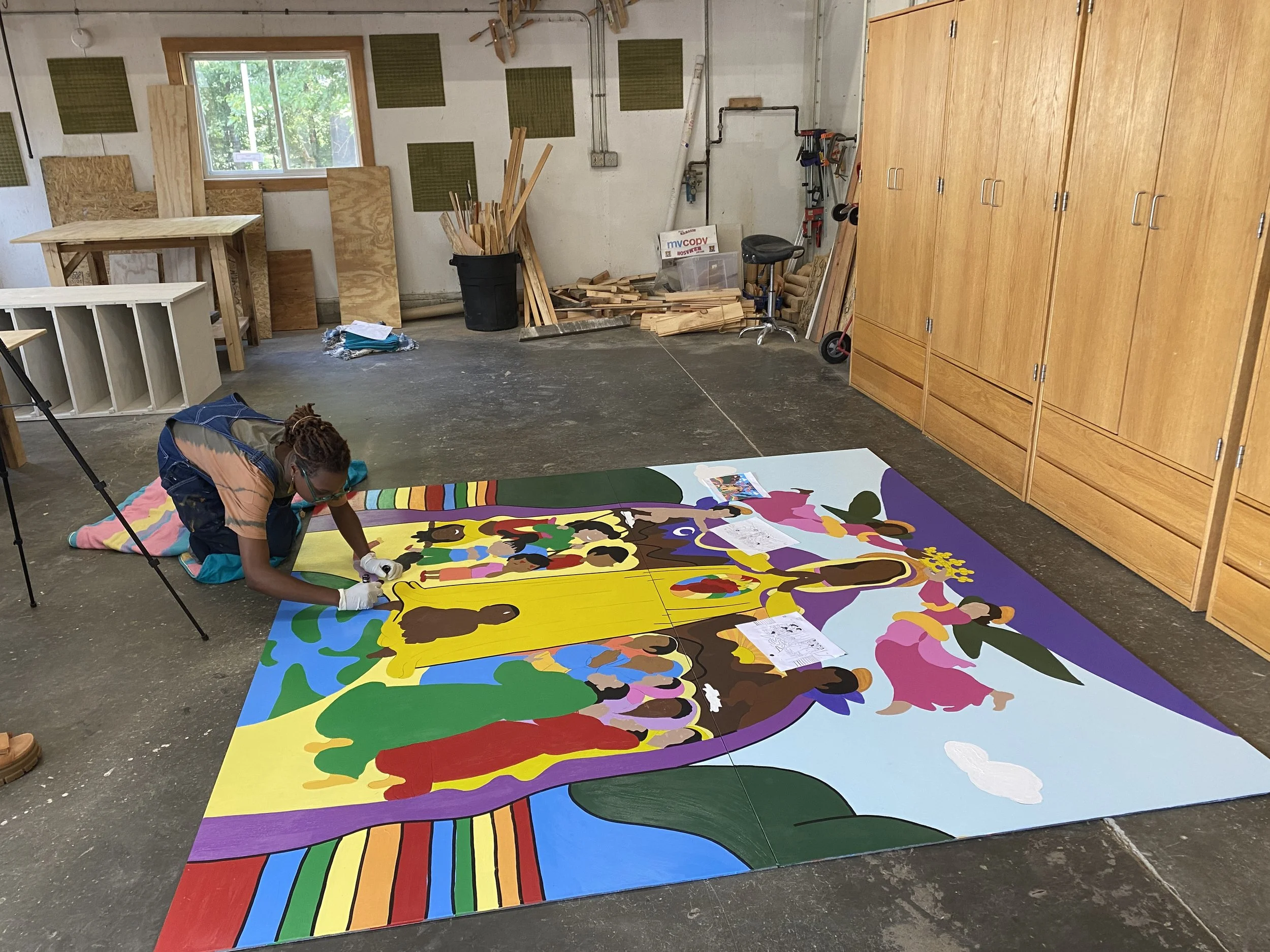 Raph Draws painting a large-scale mural on the studio floor at MakerSphere in Waterbury, VT.