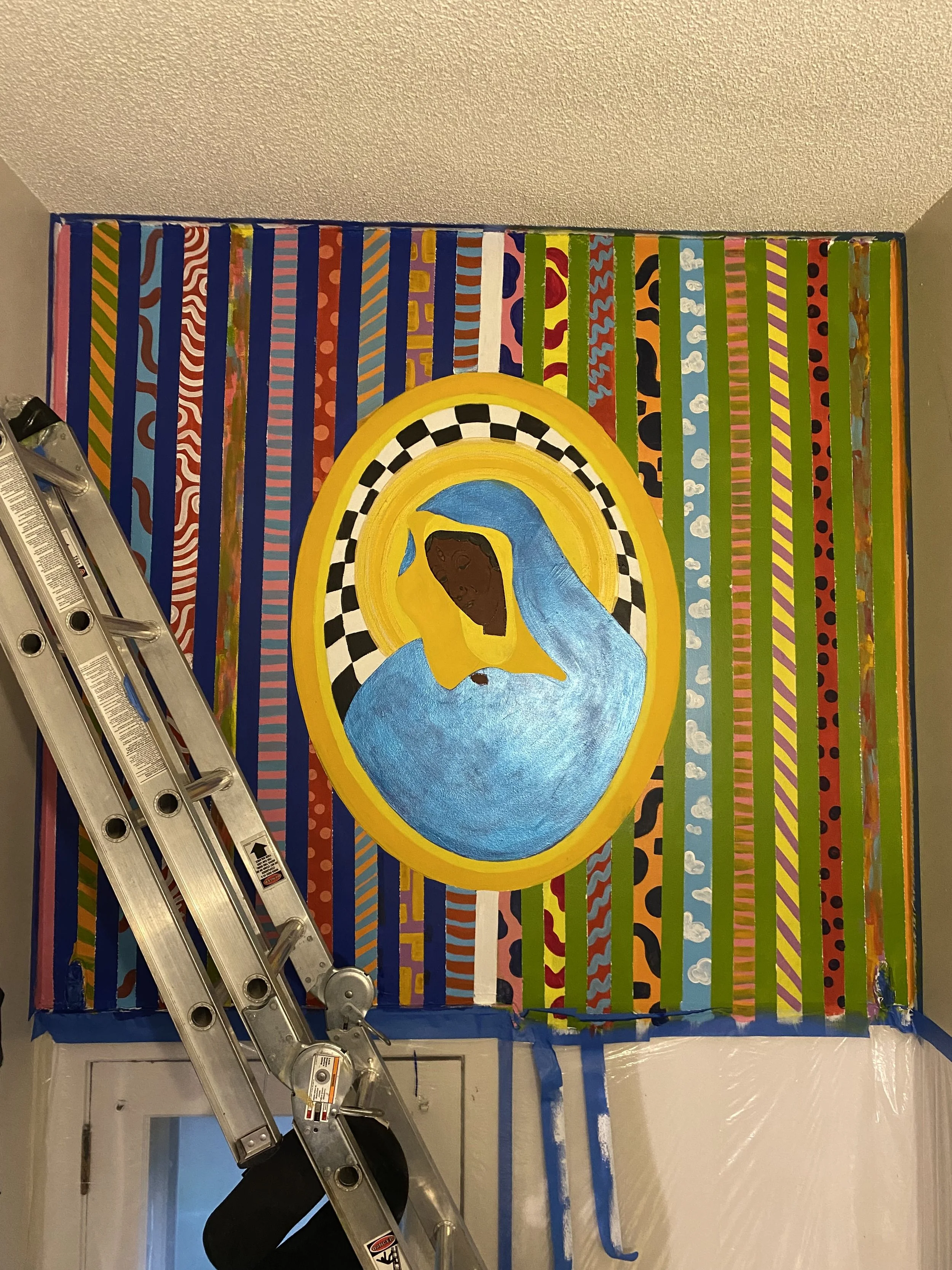 A close-up of a mural in progress showing a Black Madonna in a gold checkered halo, surrounded by vertical stripes filled with varied patterns including dots, waves, and geometric shapes in vivid colors.