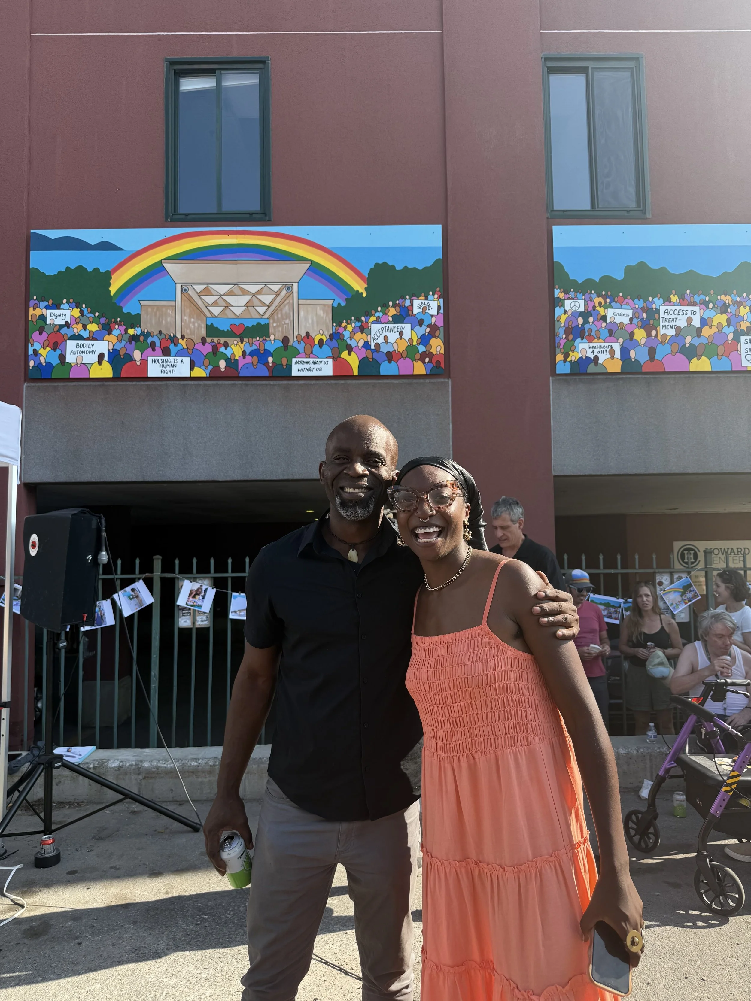 Raph Draws and collaborating artist Julio Desmont smiling in front of the Why We March mural at its installation, Burlington VT, 2025