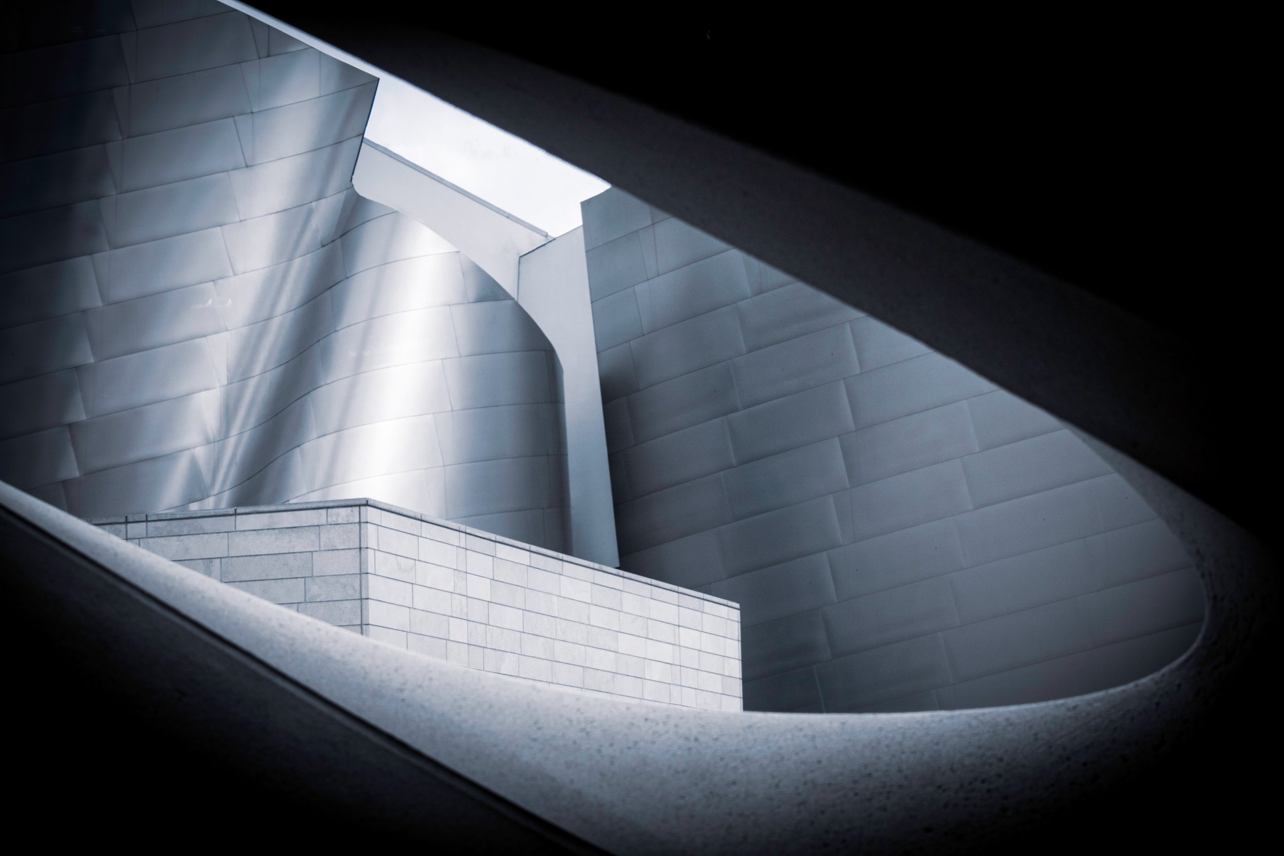 View of modern architectural building with metallic and concrete surfaces, seen through window frame.