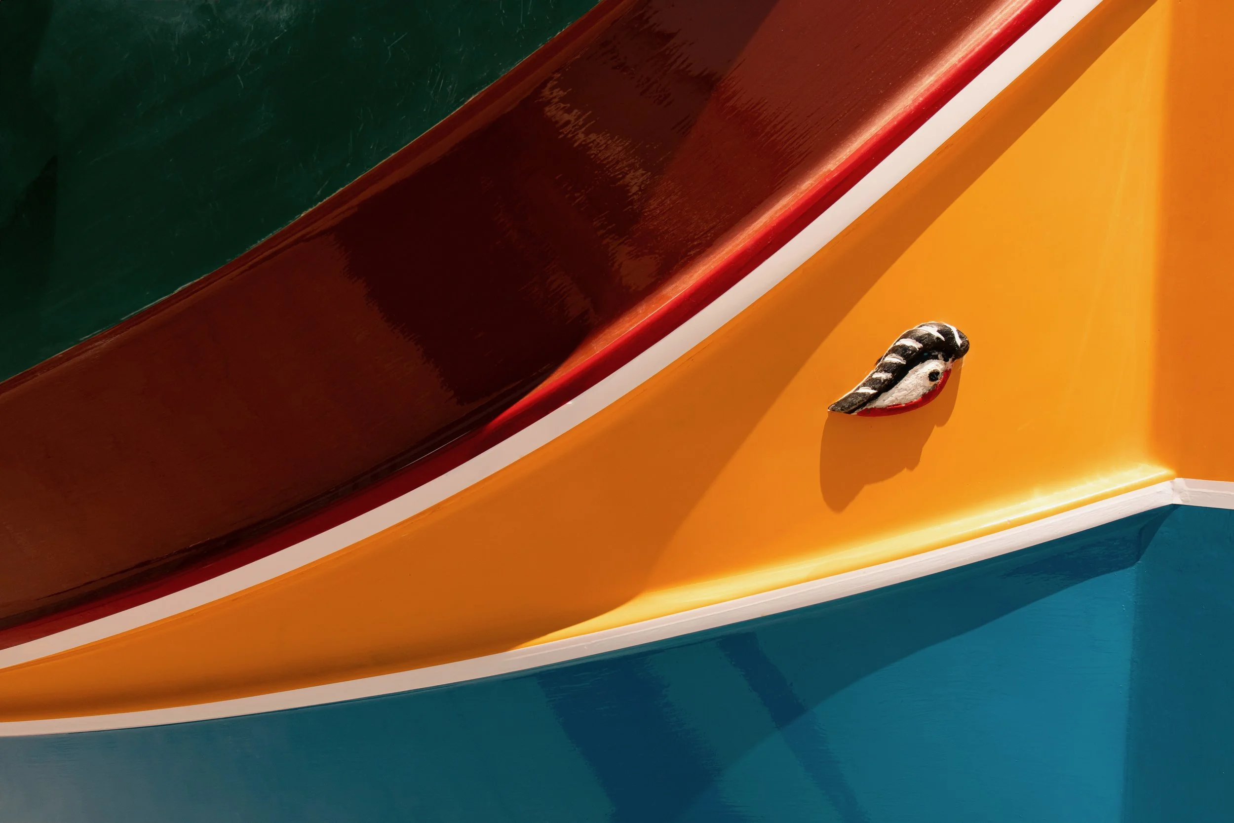 Close-up of a colorful boat with green, red, yellow, and blue sections, and a decorative black and white element on the yellow part.