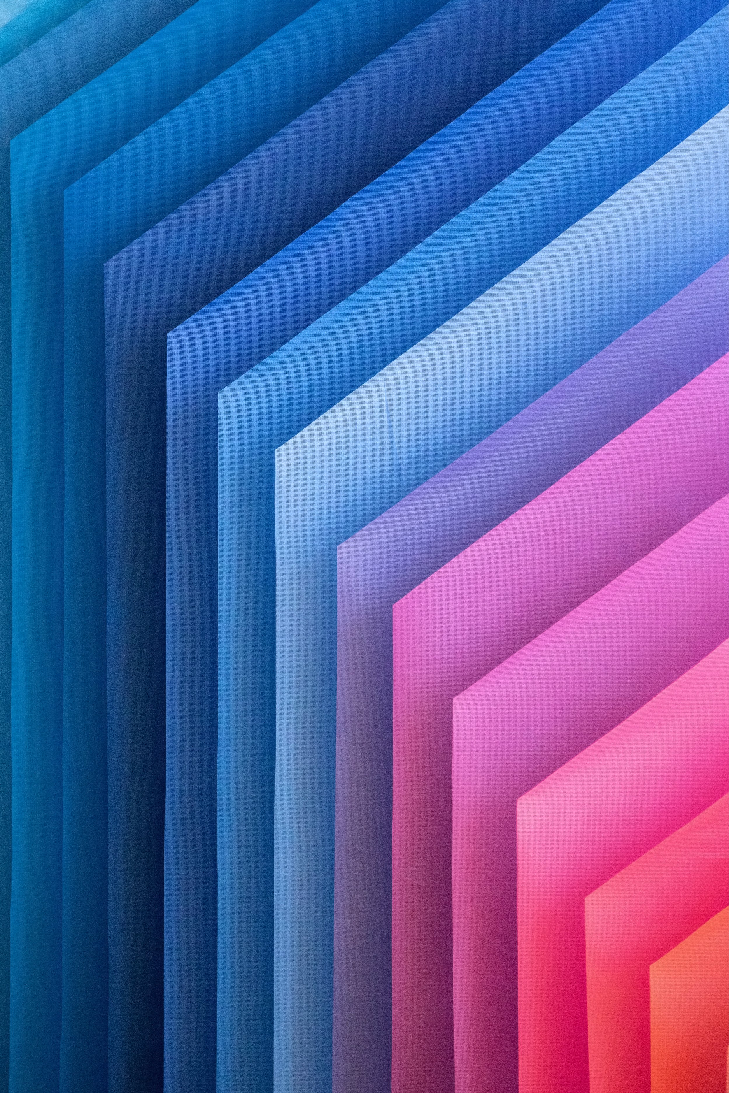 Colorful geometric pattern with layered, curved shapes in blue, purple, pink, and orange hues.