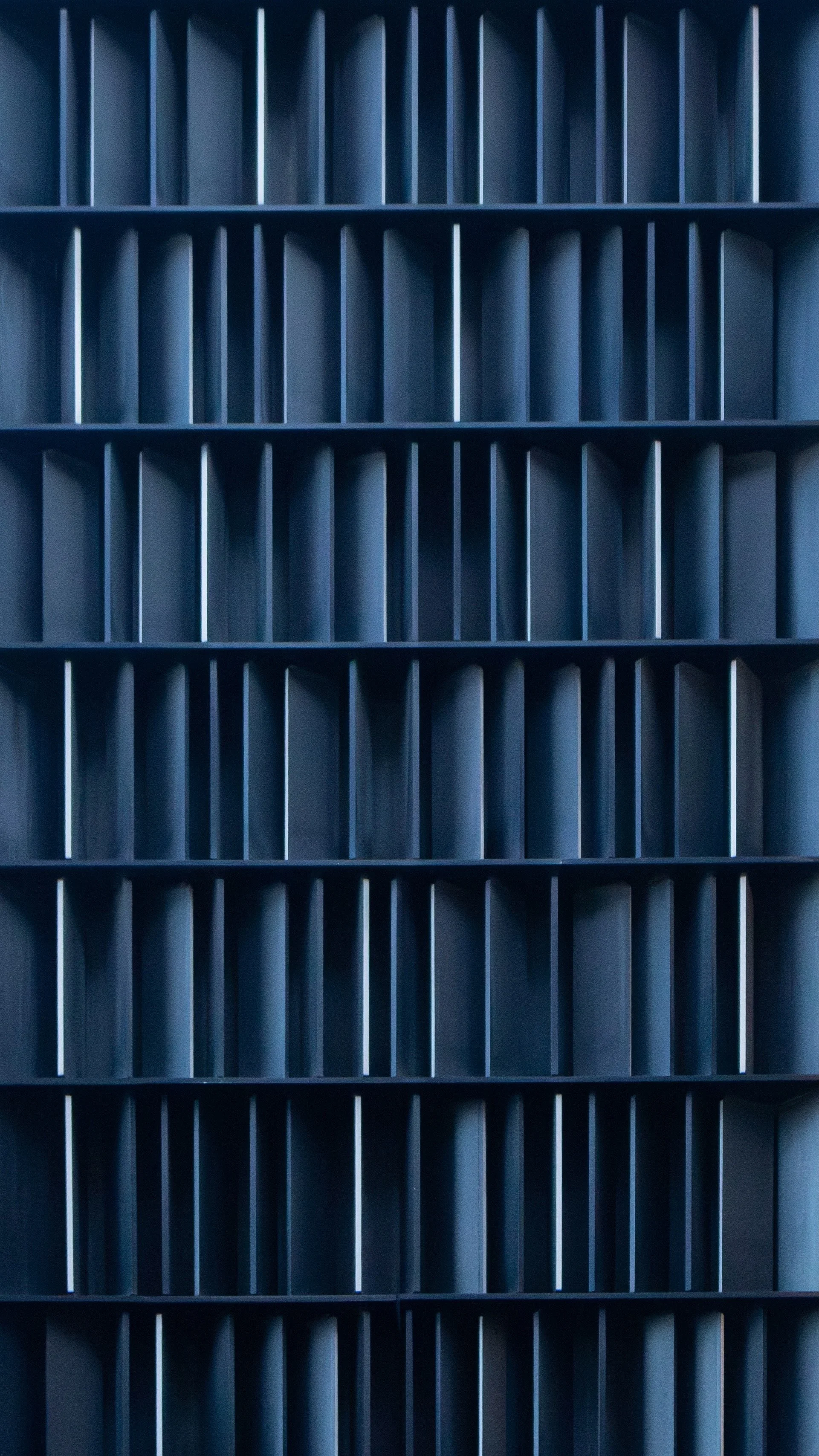 A close-up of a blue industrial or office storage shelving unit with multiple empty rectangular compartments.