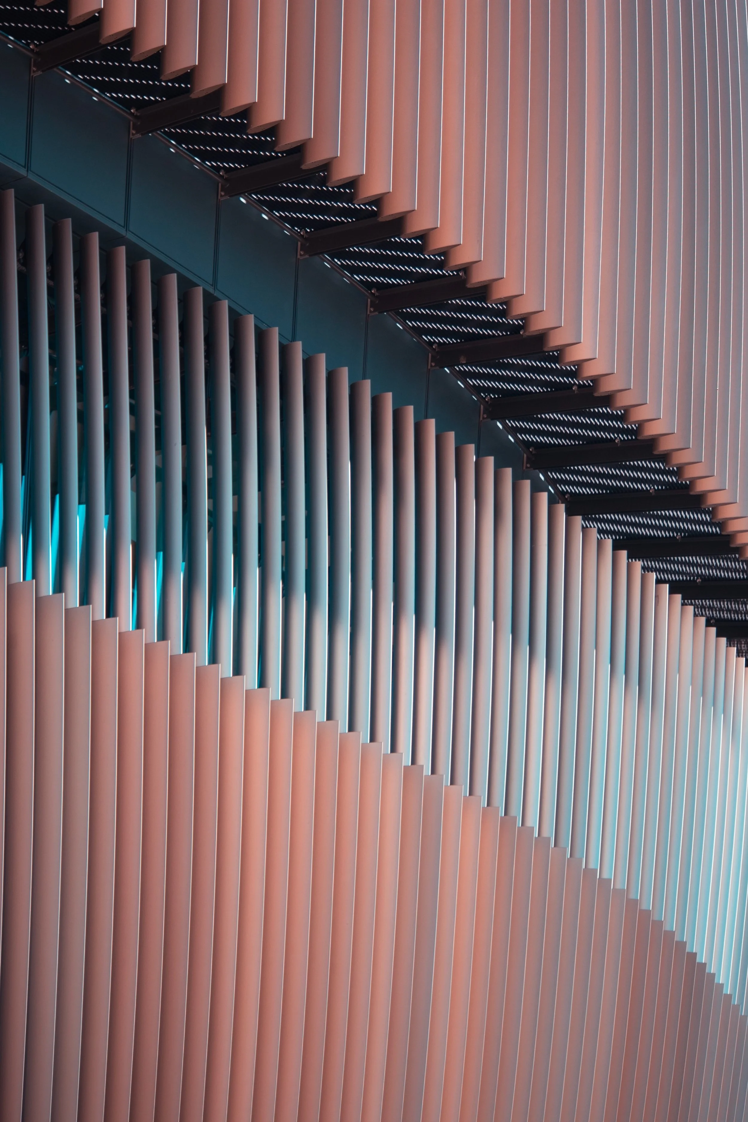 Close-up view of architectural elements with horizontal copper or bronze-colored louvers and vertical metallic fins, possibly part of a building exterior or modern sculpture.