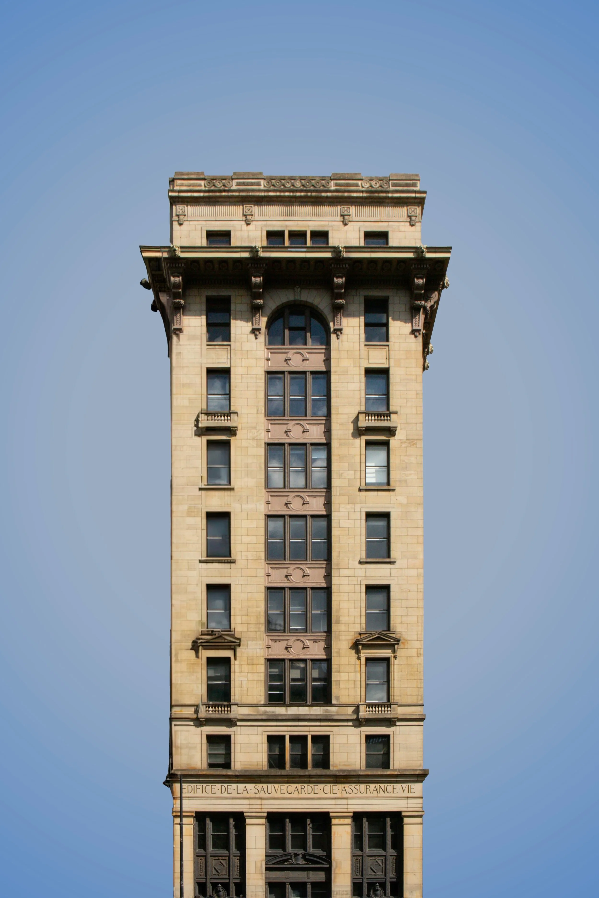 A tall historic building with ornate architectural details, set against a clear blue sky.