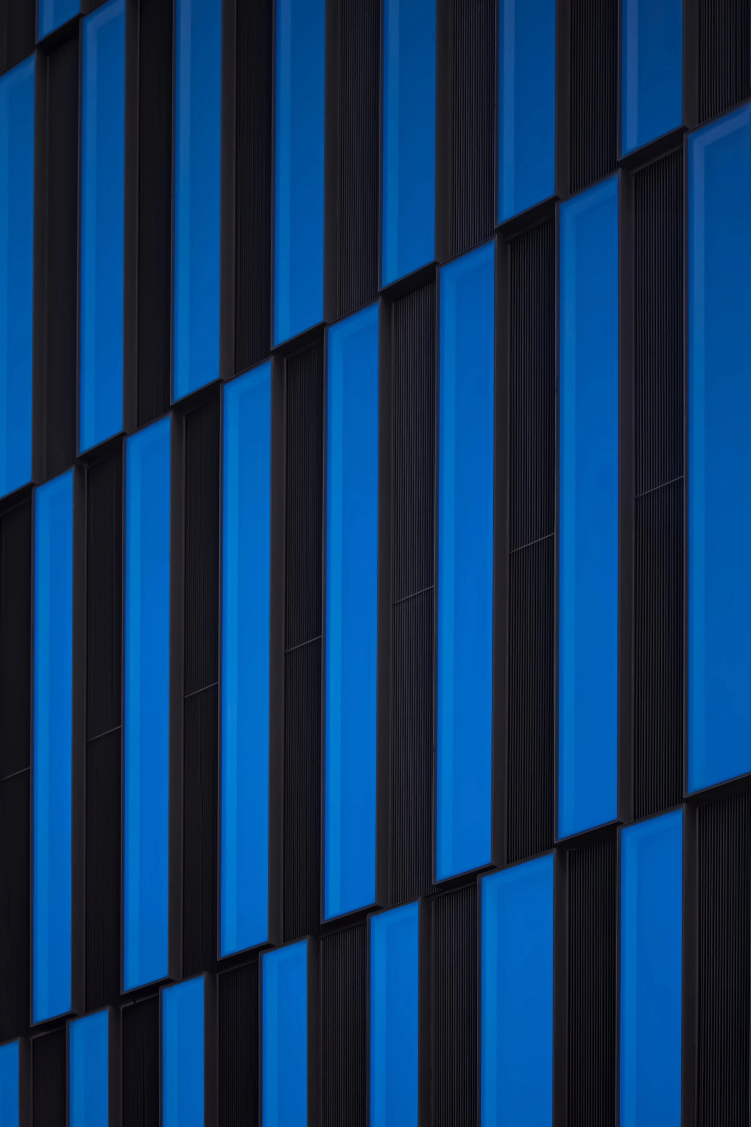 Close-up of a modern building's exterior with alternating vertical blue and black panels.