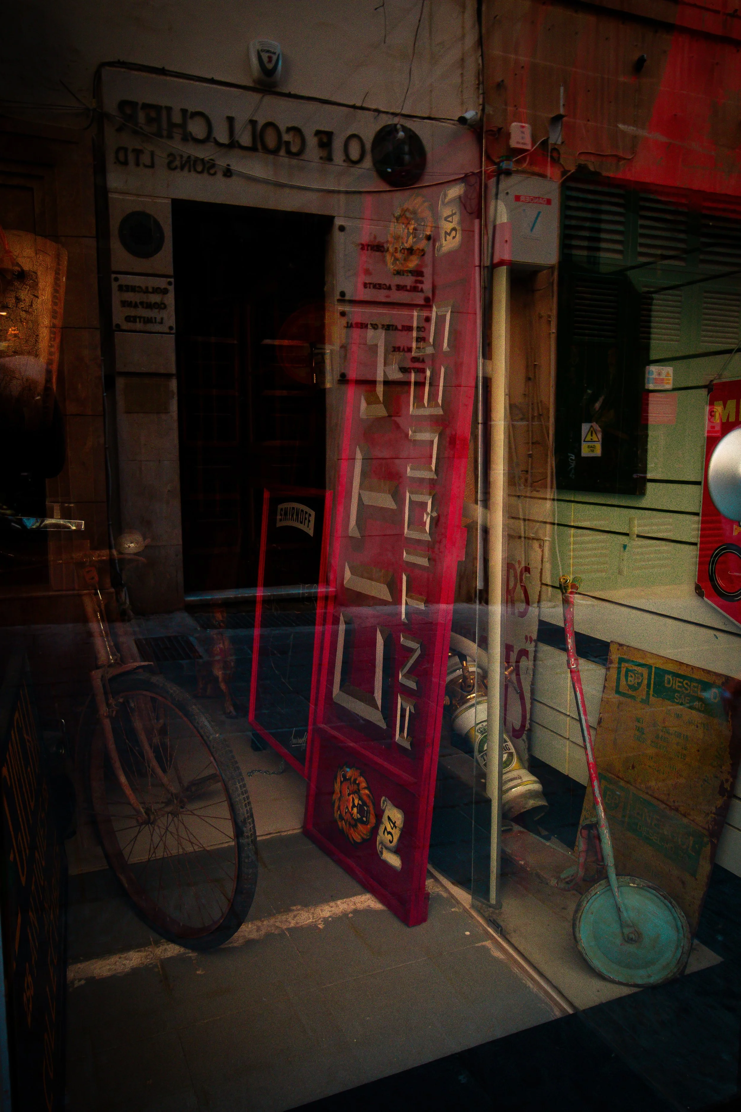 Display of various signs and objects on a shop window, including a red sauna sign, a vintage bicycle, a streetlamp, and a box of diesel fuel.