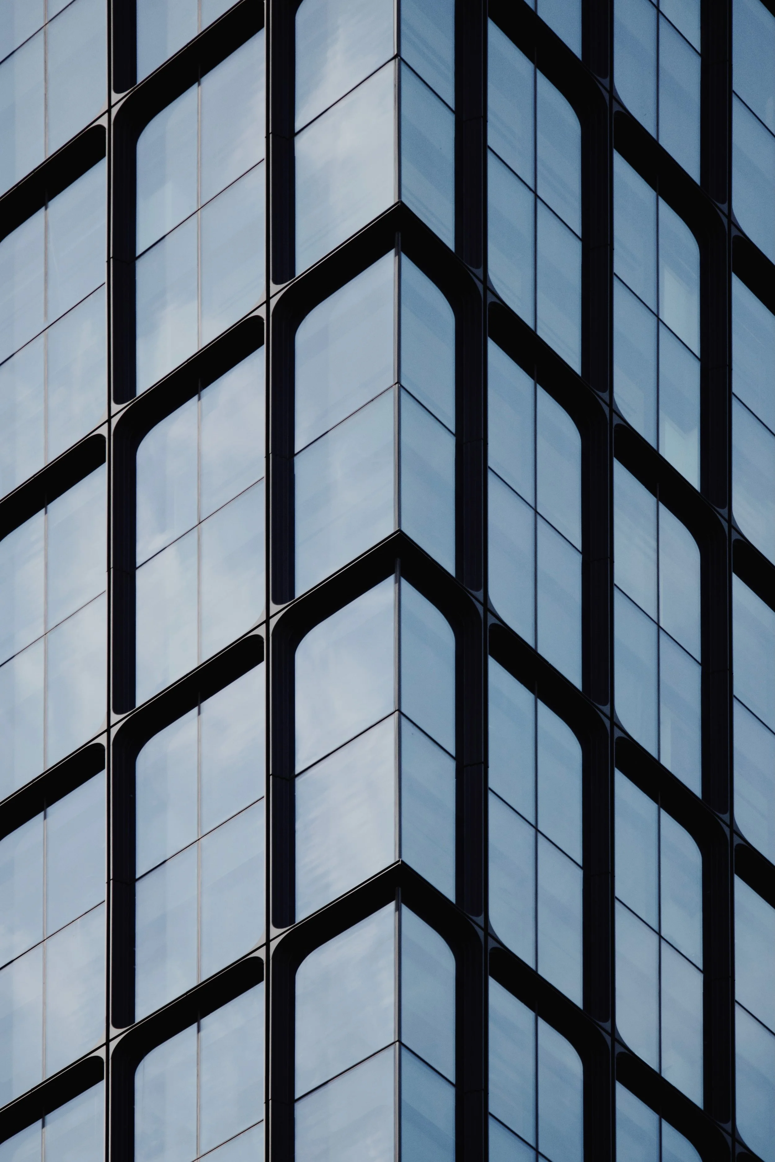 Close-up of a modern glass office building with reflective windows and a geometric grid pattern.