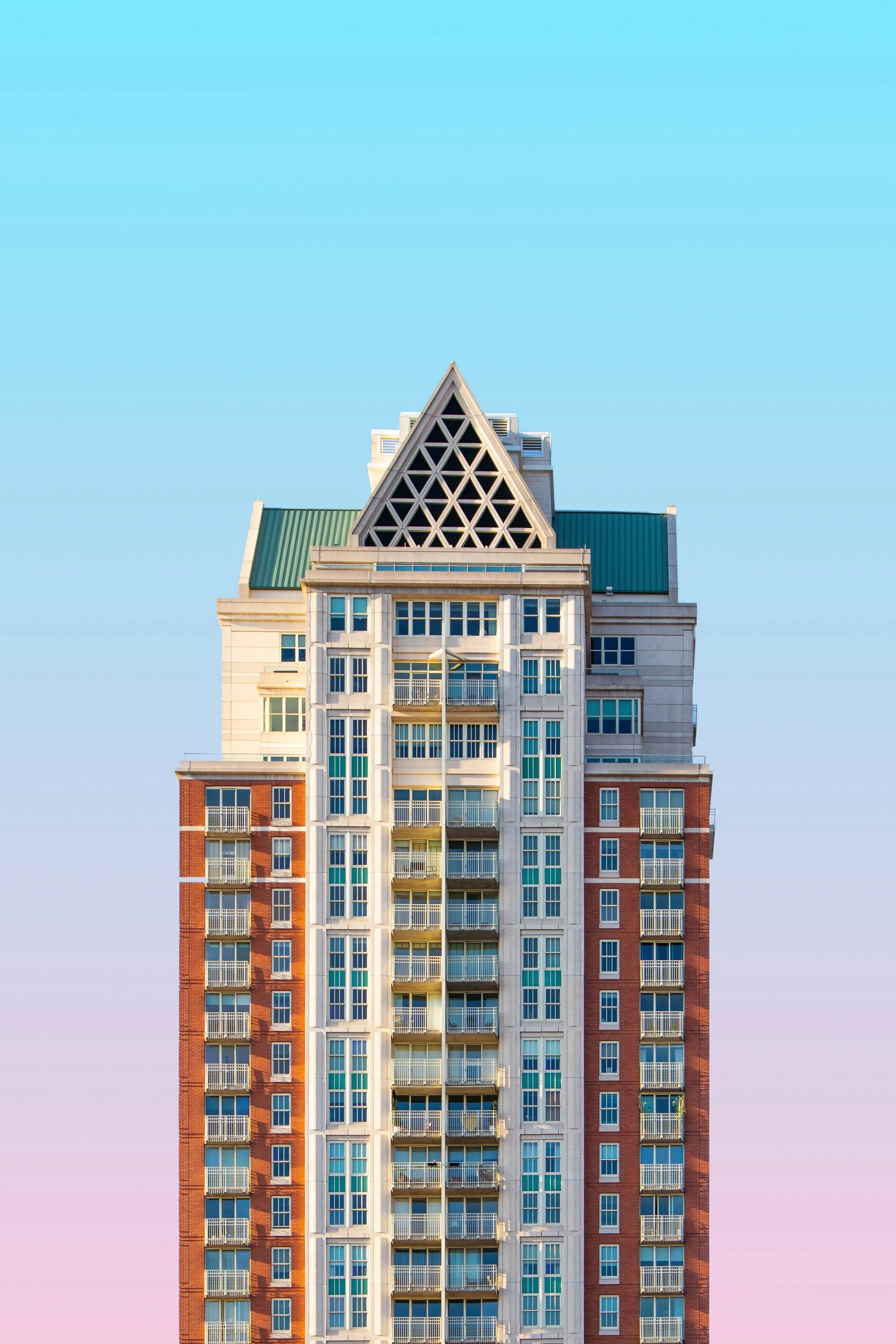 A tall modern apartment building with a distinctive triangular rooftop against a clear sky.
