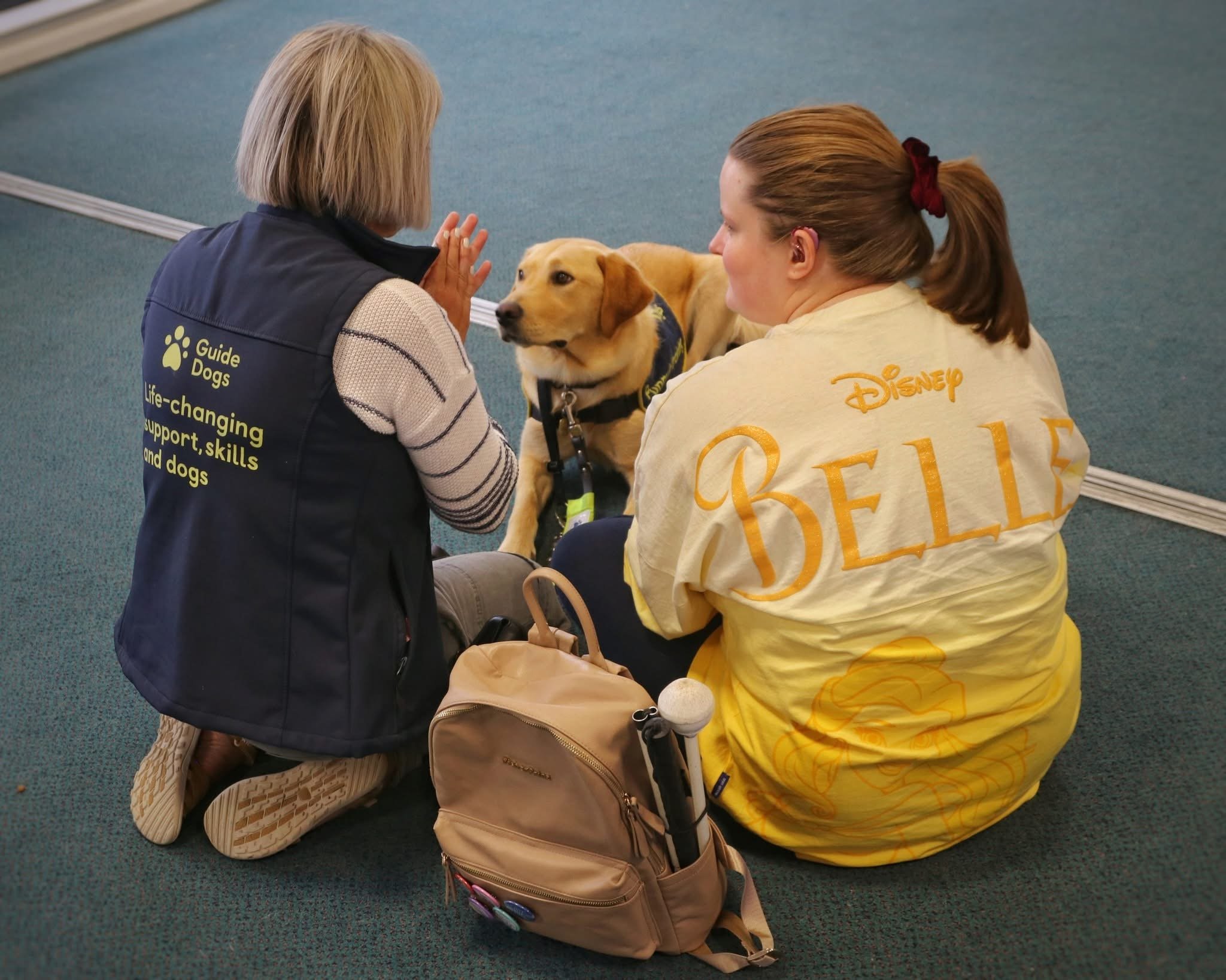 Hope attending an event at Forth Valley Sensory Centre, sitting with a guide dog puppy and a puppy raiser. Image  Credit - Image taken at an event at Forth Valley Sensory Centre