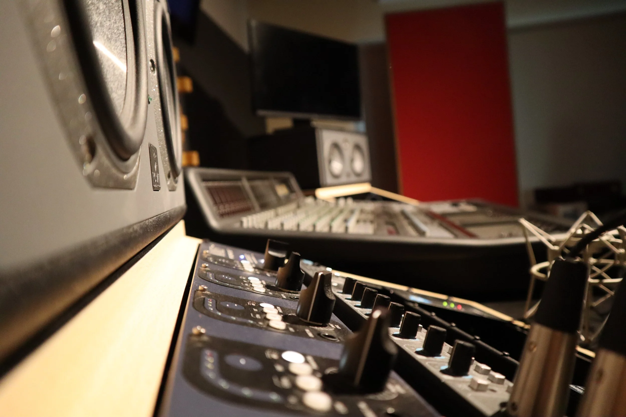 Estudio de grabación con consola de mezcla, monitores de audio, y equipo de audio profesional.