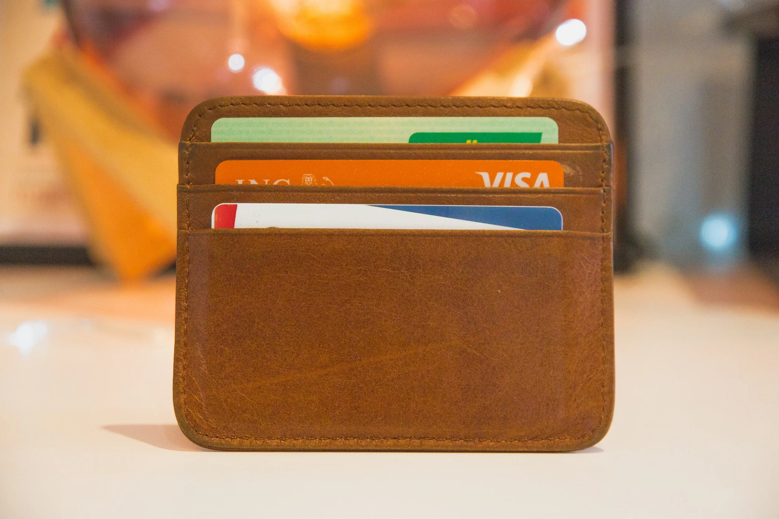 image of a small brown wallet. The tops of three cards can be seen, one credit card, and the other two might be credit cards or health insurance cards.