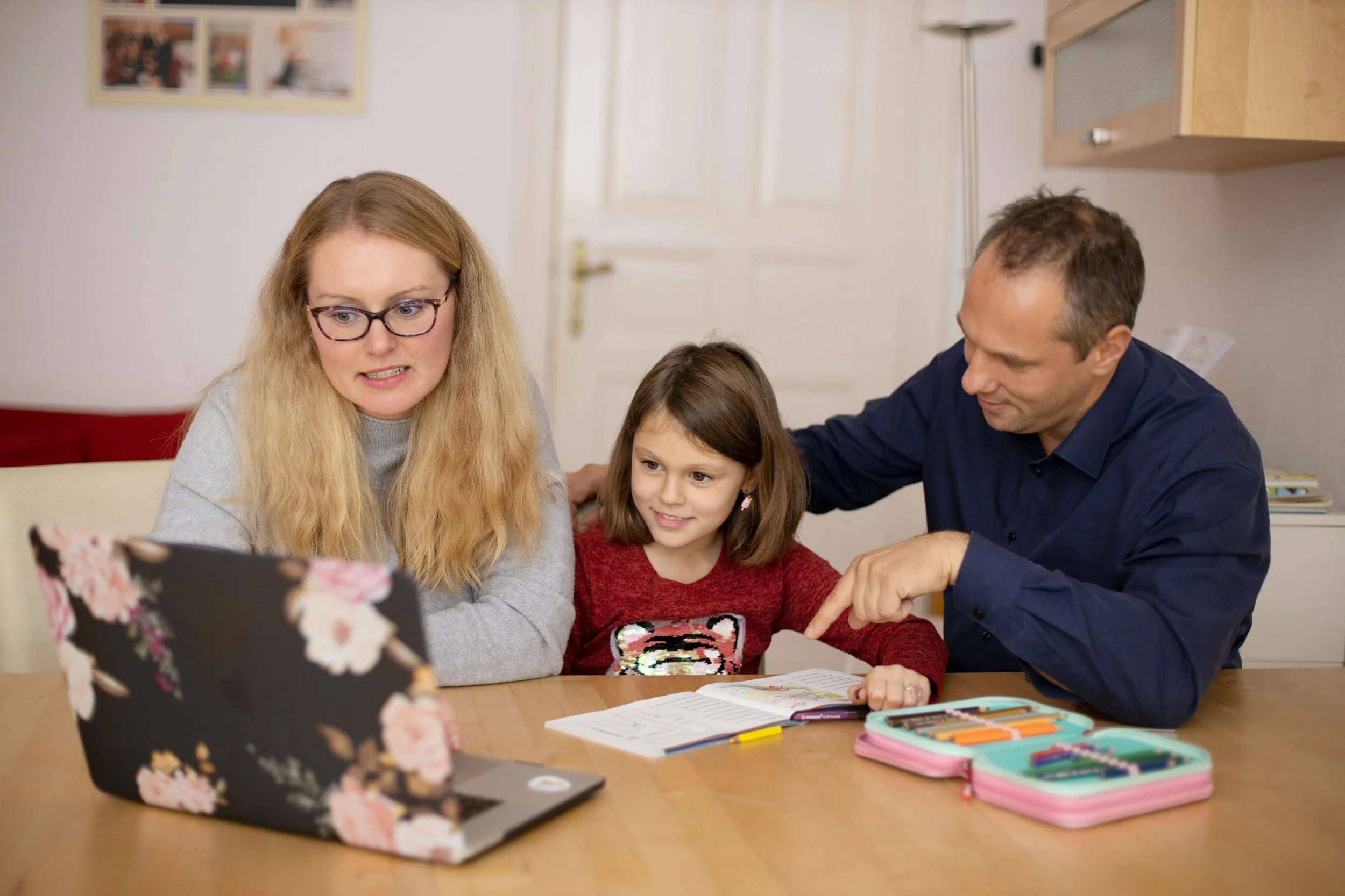 Mother and father helping daughter with homework. Mother looks stressed about the school work.