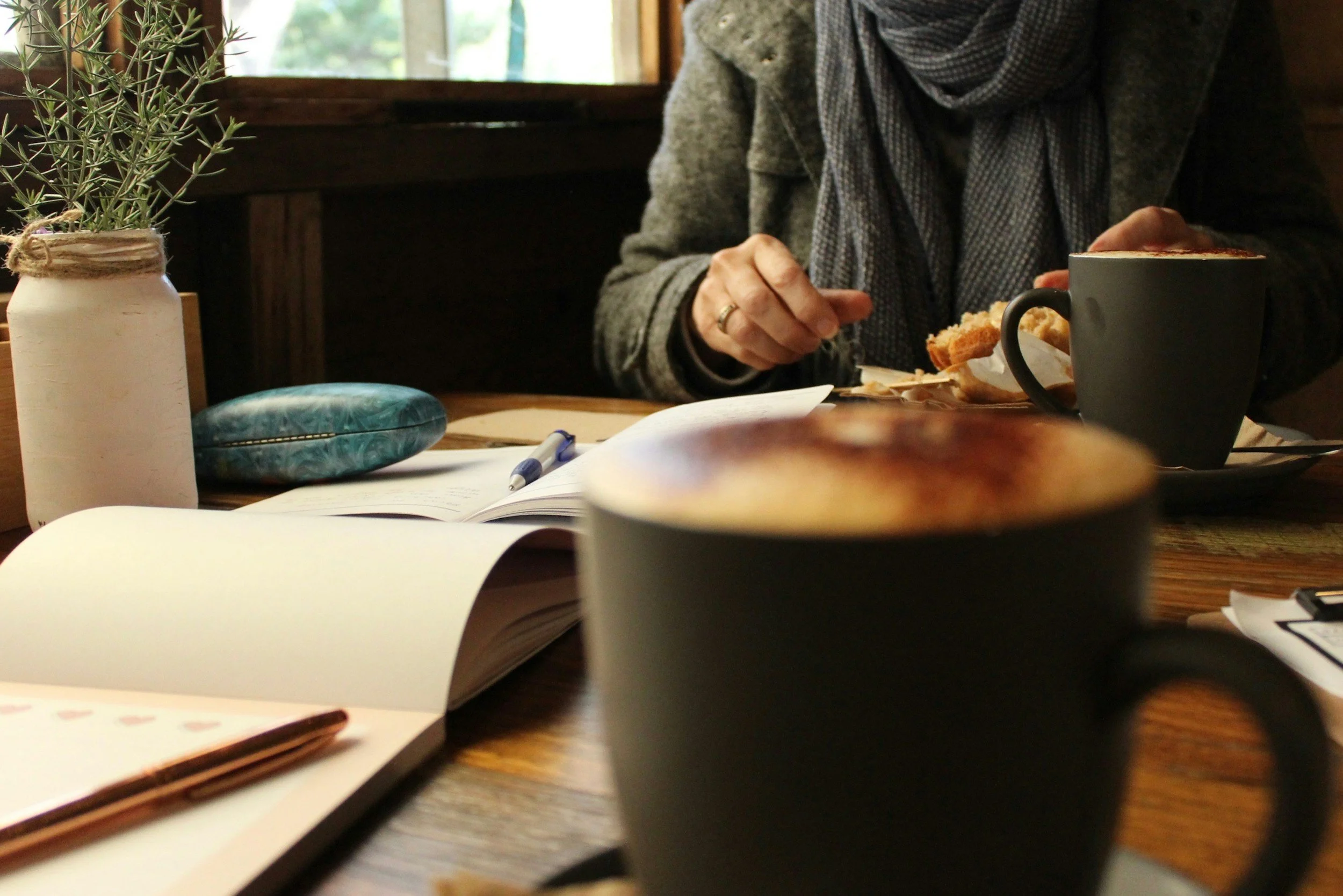 Adult sitting with a journal and coffee, reflecting during early fall — representing the September 'behind' feeling