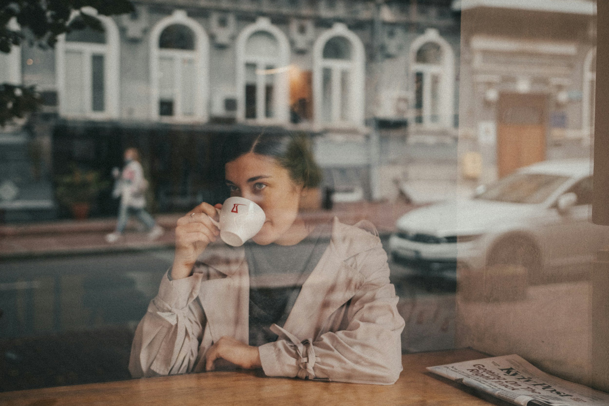 Parent taking a quiet moment with coffee by a window in late fall, holiday stress