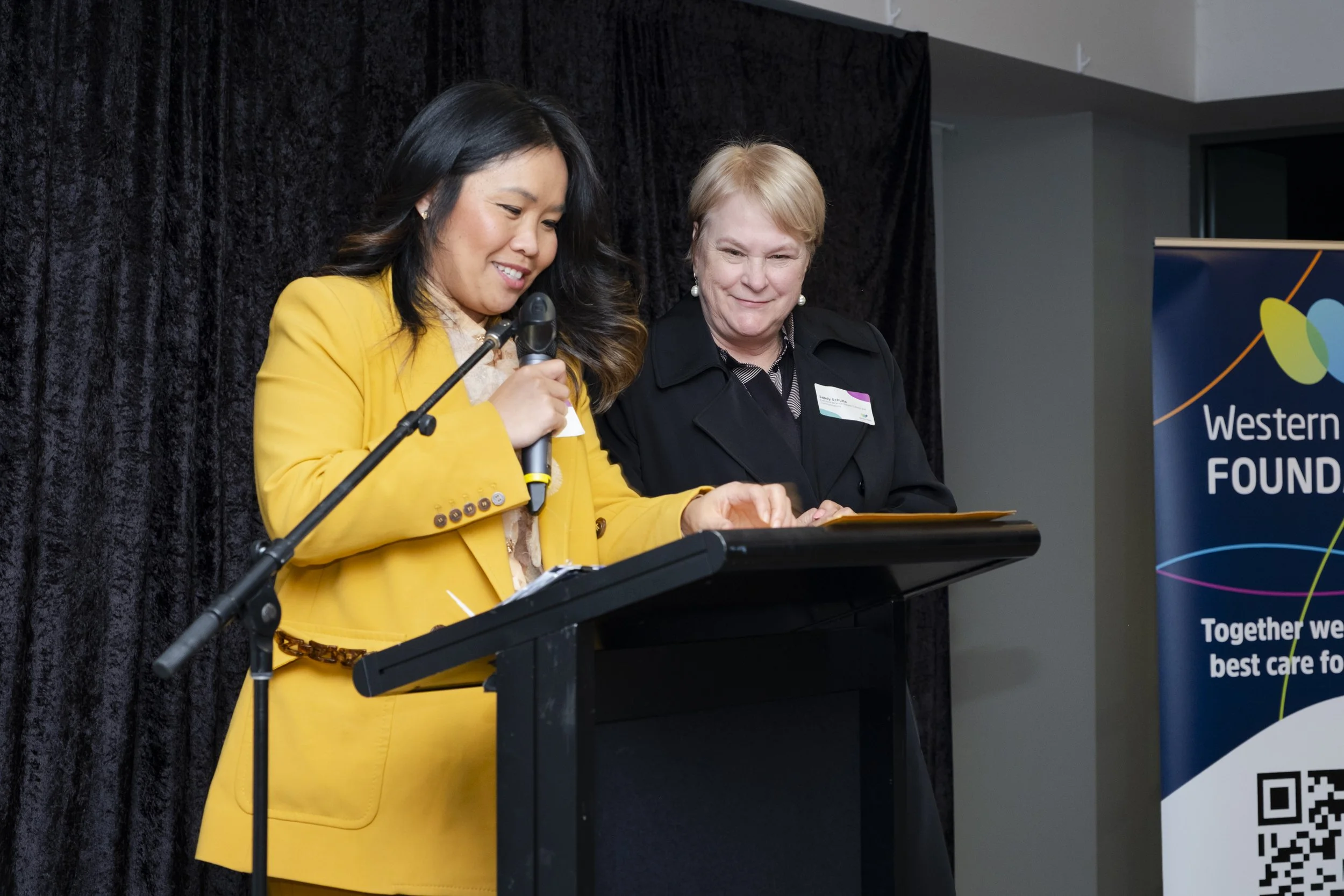 MC presenting at a podium alongside a guest speaker at a Western Health Foundation corporate event, Melbourne