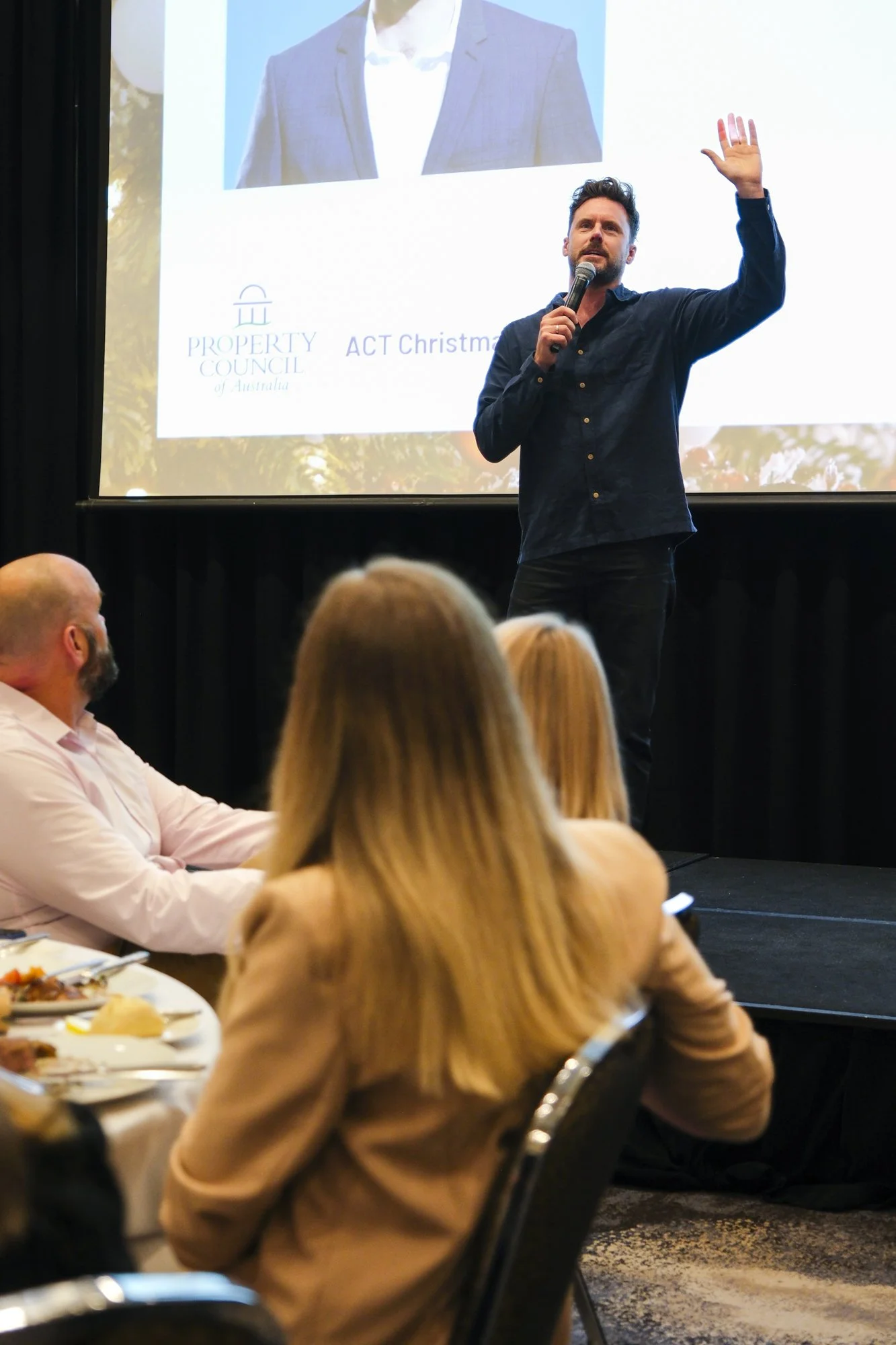 Comedian Dave Thornton performing on stage at a Property Council of Australia Christmas event, Hyatt Canberra