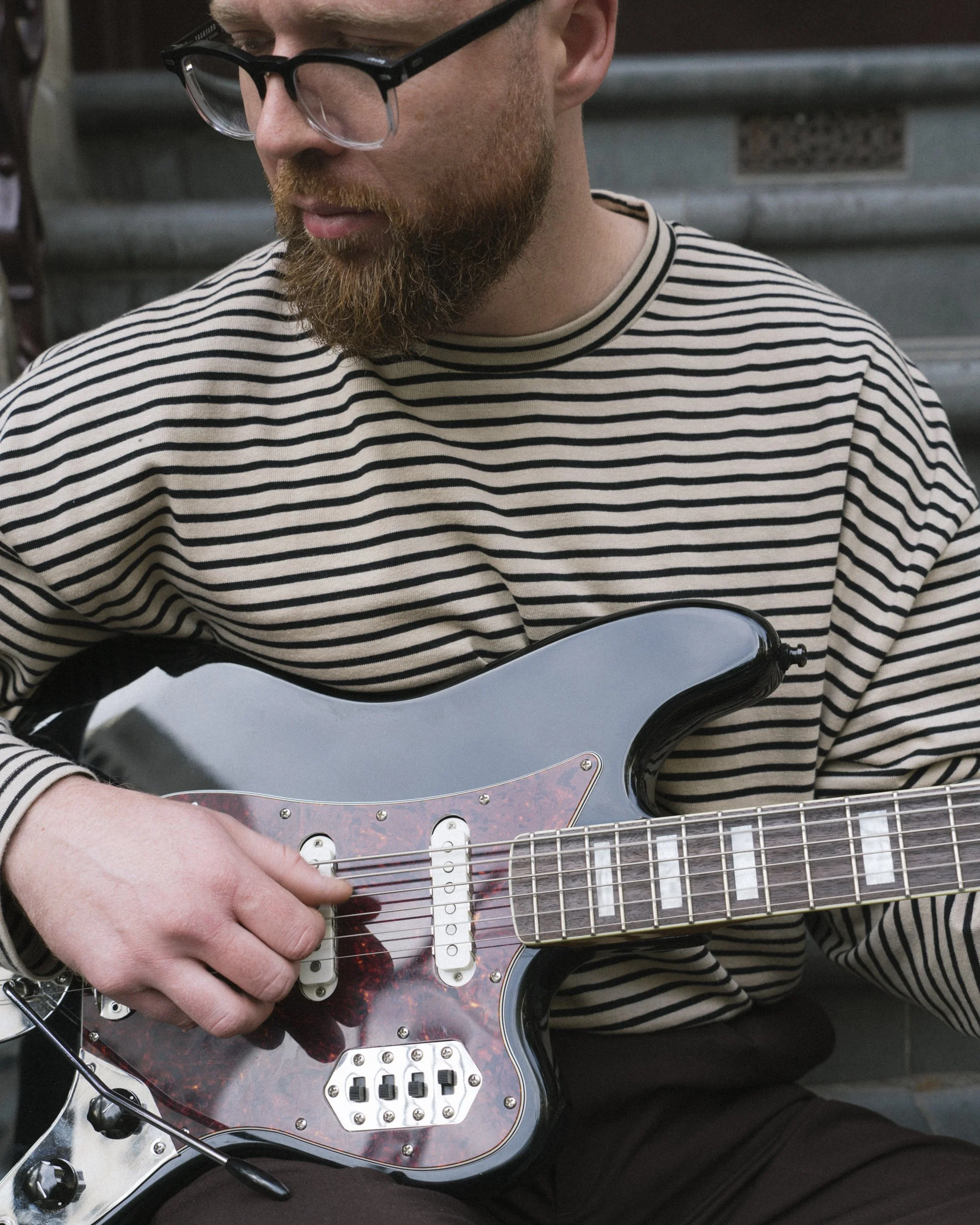 Close-up of musician's hands playing a vintage electric guitar with tortoiseshell pickguard, Melbourne CBD steps